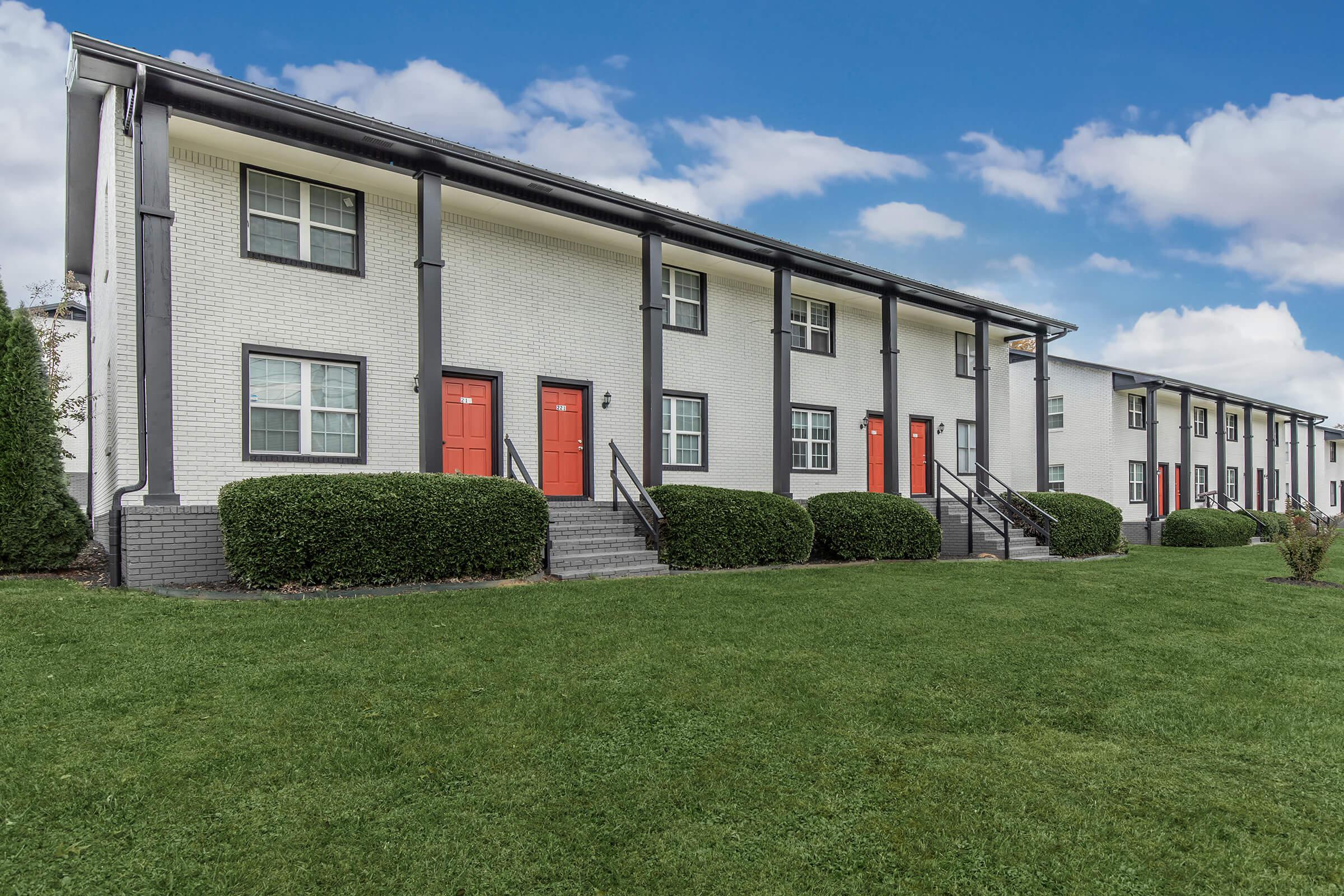 Front view of the Elements44 Townhomes. Green grass, beautifully cut bushes, and the outside view of the 2 Bed 1.5 Bath Townhomes