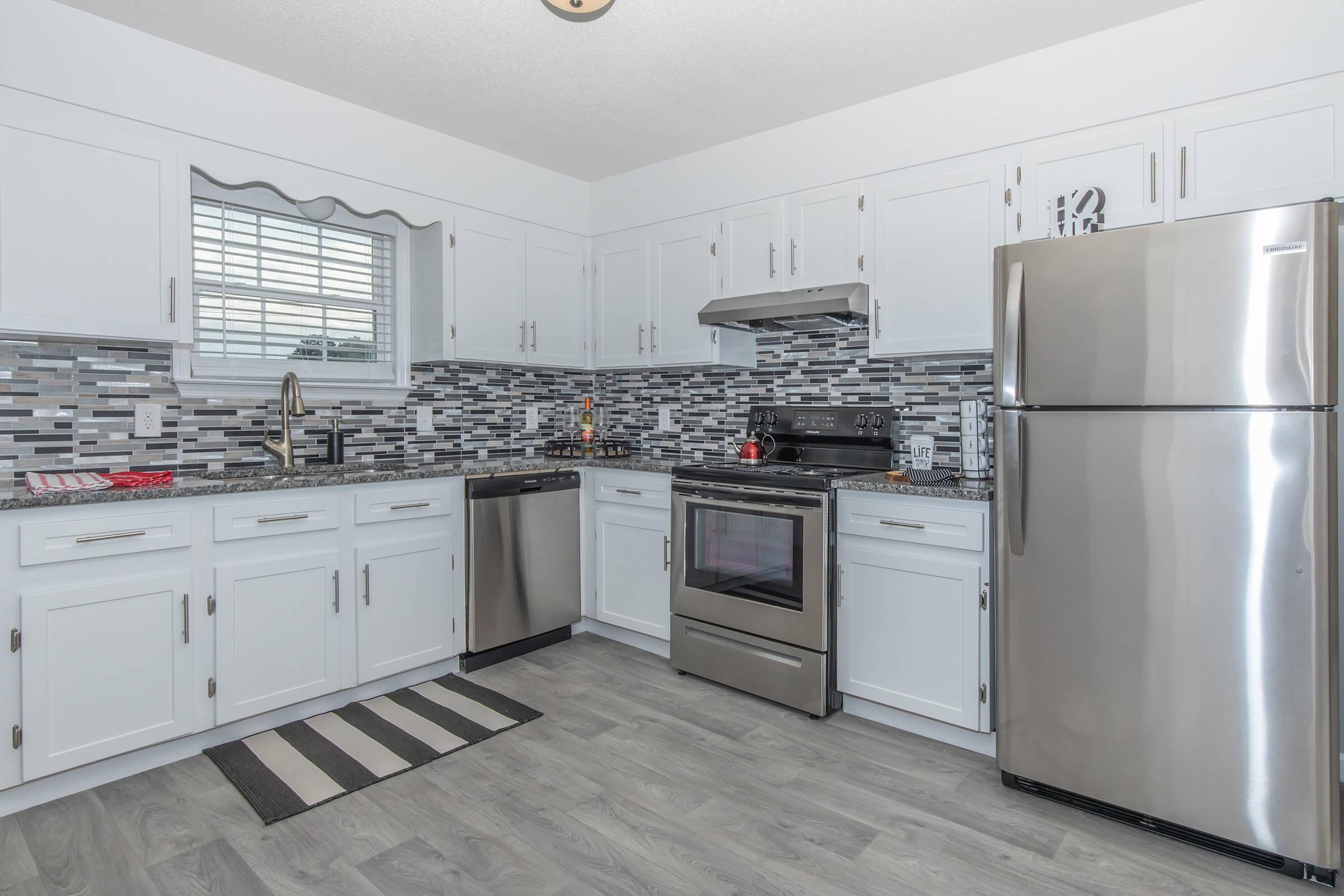 Elements44 Townhomes kitchens showcase stainless steel appliances, white cabinets, tile backsplashes and hardwood floors