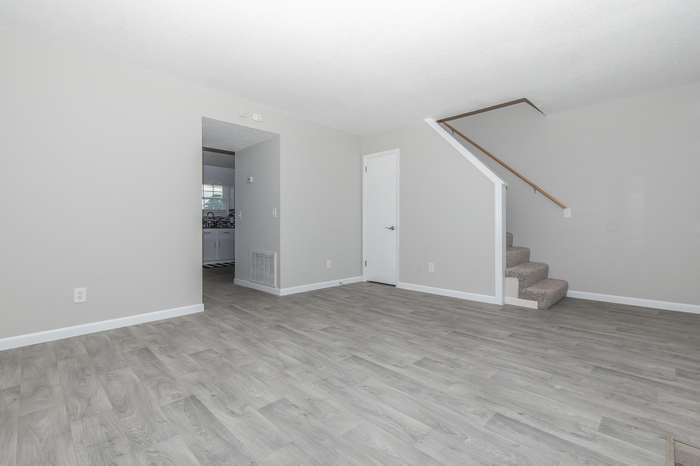 The Elements44 Townhomes living room with hardwood floors, a staircase, and the entryway to the kitchen.