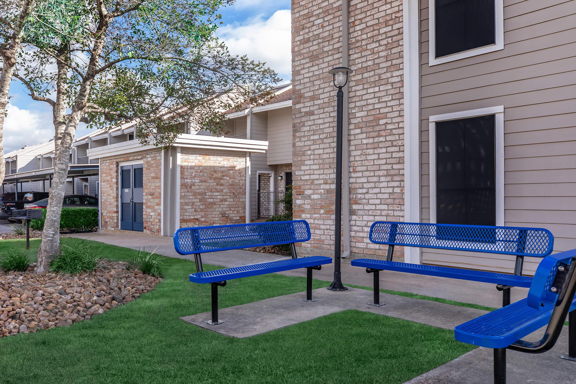 a blue bench in front of a brick building