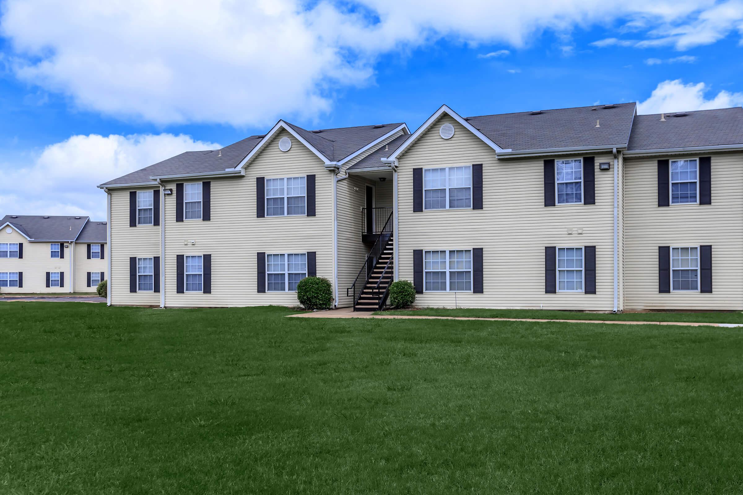 a large brick building with a grassy field
