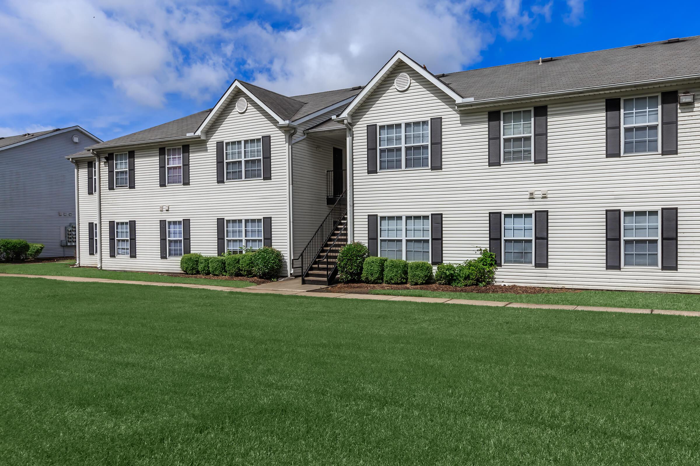 a large brick building with grass in front of a house