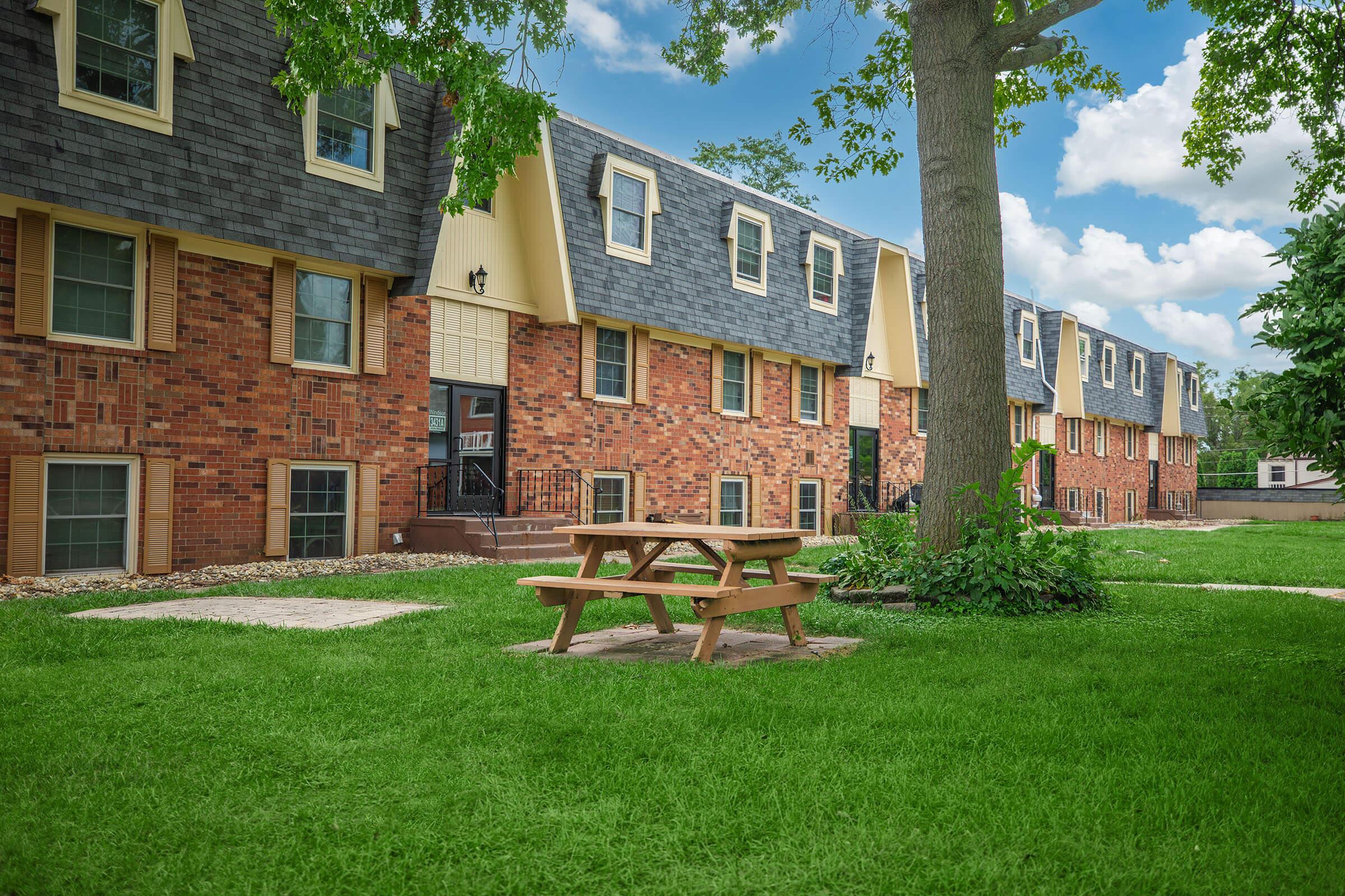 Picnic tables and green lawn beside apartment building at Homewood Manor Apartments in Moline, IL