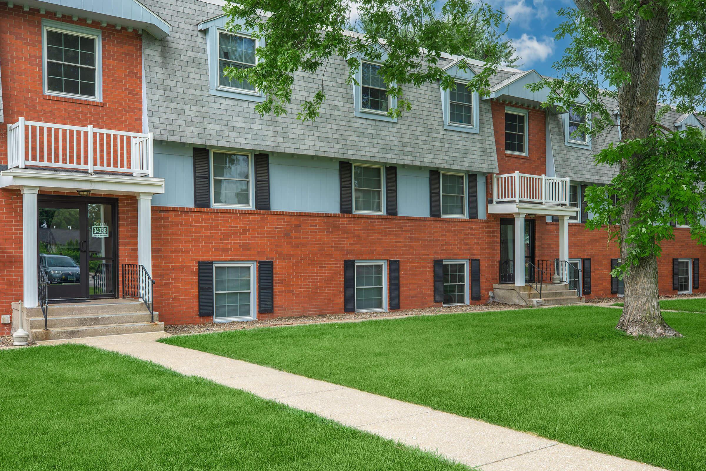 Red brick apartment building with manicured green lawn at Homewood Manor Apartments in Moline, IL