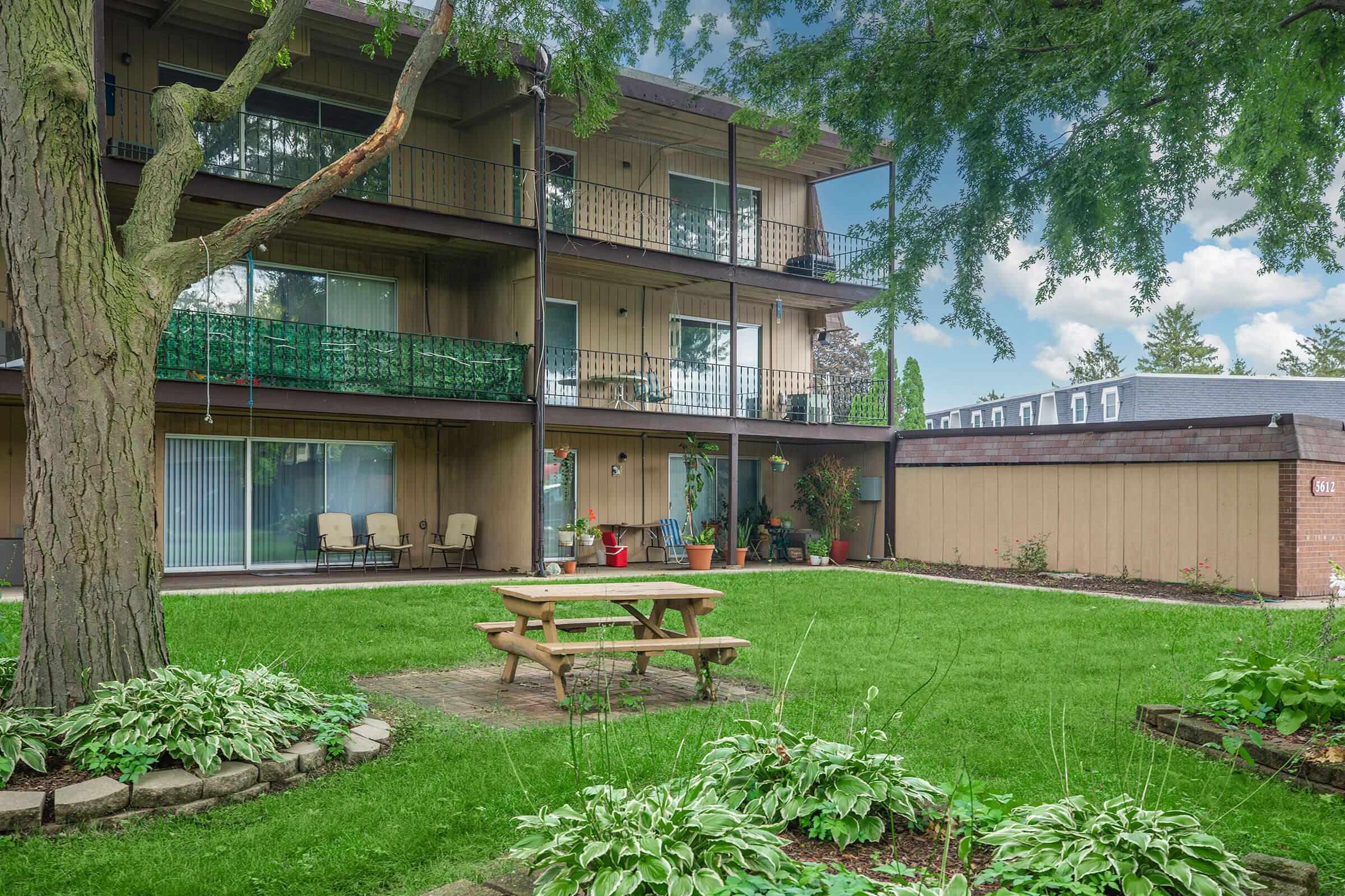 Shaded picnic area with tree and benches at Homewood Manor Apartments in Moline, IL