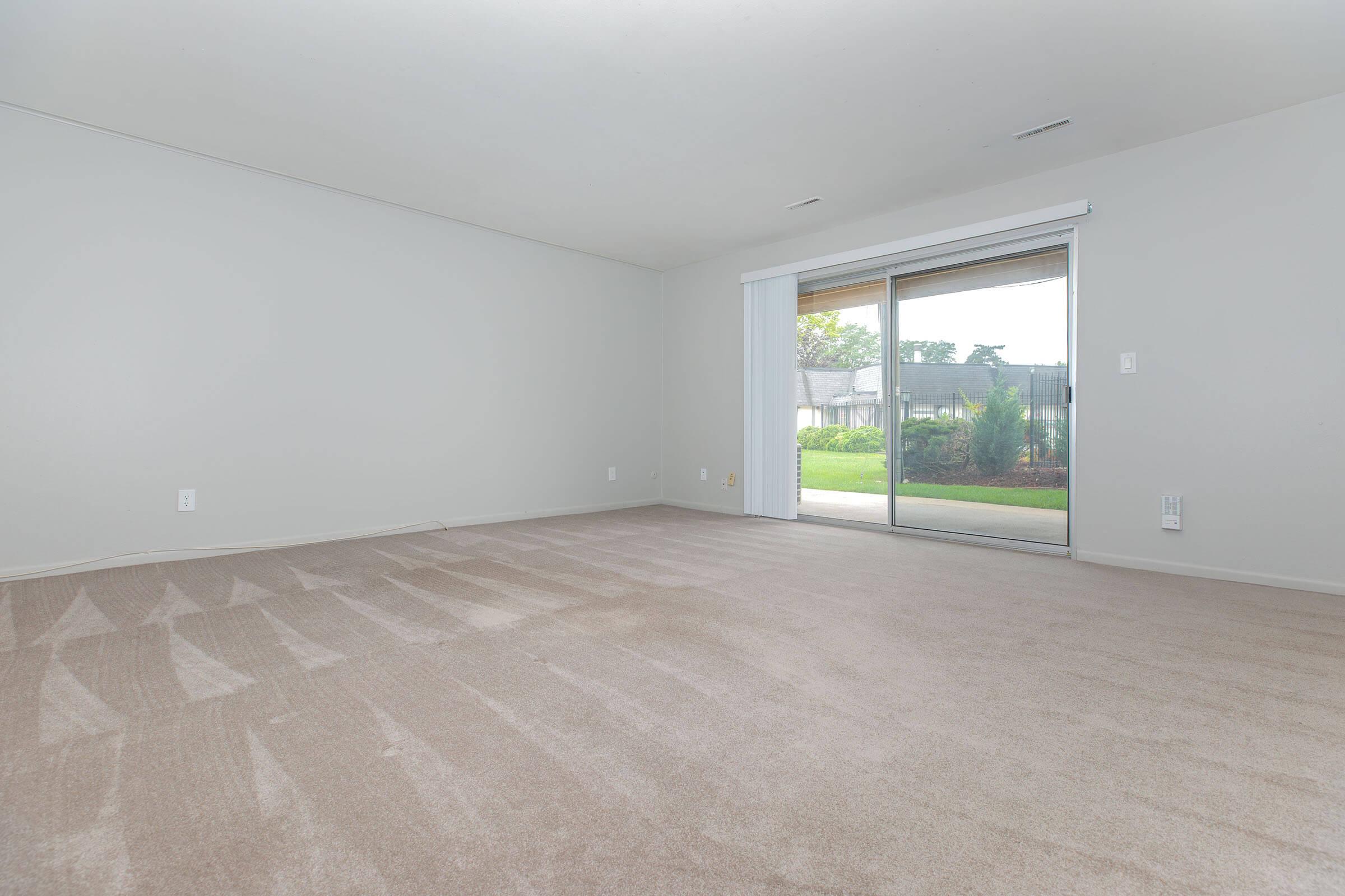 Bright living room with large sliding glass doors and carpet flooring at Homewood Manor Apartments in Moline, IL