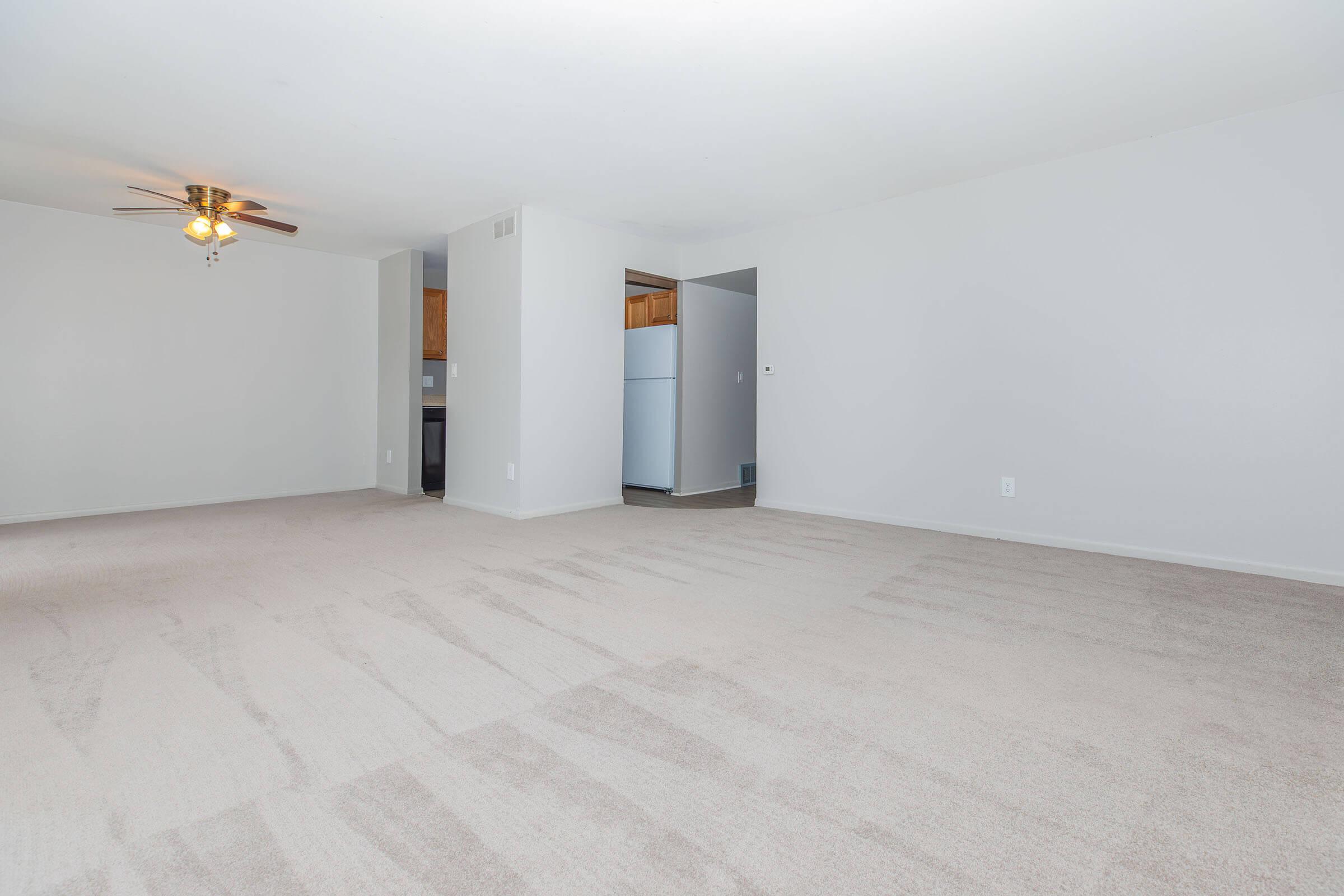 Open-concept living space with ceiling fan and carpeted flooring at Homewood Manor Apartments in Moline, IL