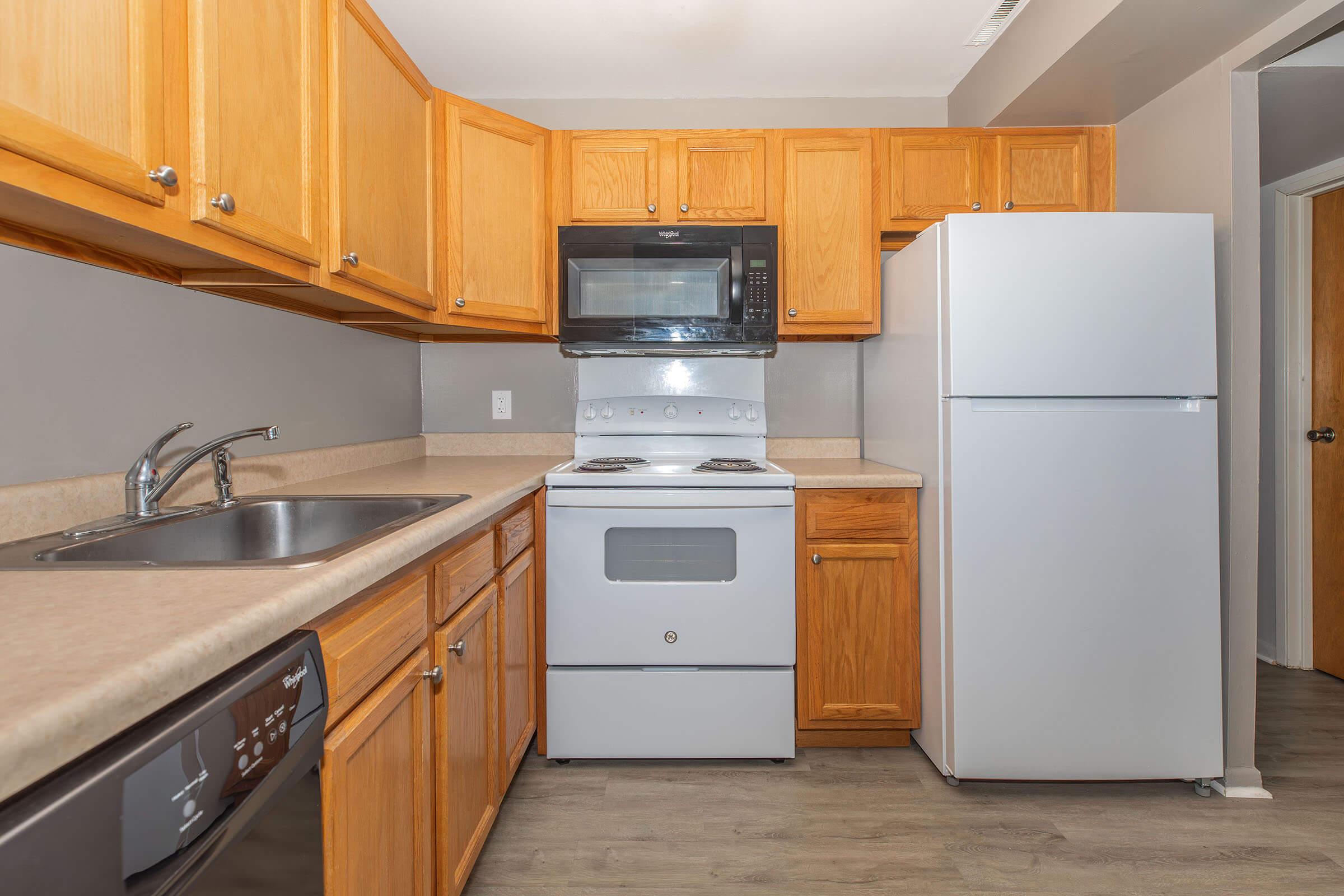 Kitchen with wood cabinetry, refrigerator, and stove at Homewood Manor Apartments in Moline, IL