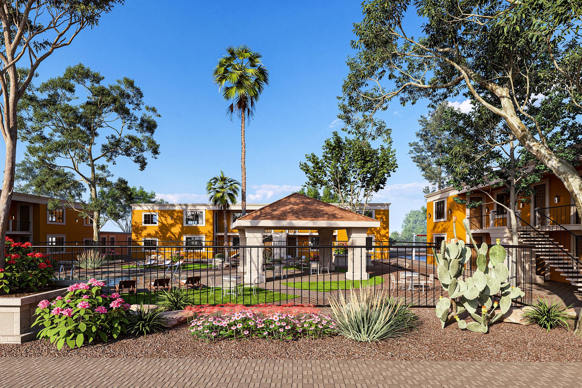 A vibrant courtyard featuring lush greenery and colorful flowers, surrounded by buildings painted in warm yellow hues. A central gazebo with a brown roof is set near a swimming pool. Palm trees and cacti add to the tropical atmosphere, creating a serene outdoor space.