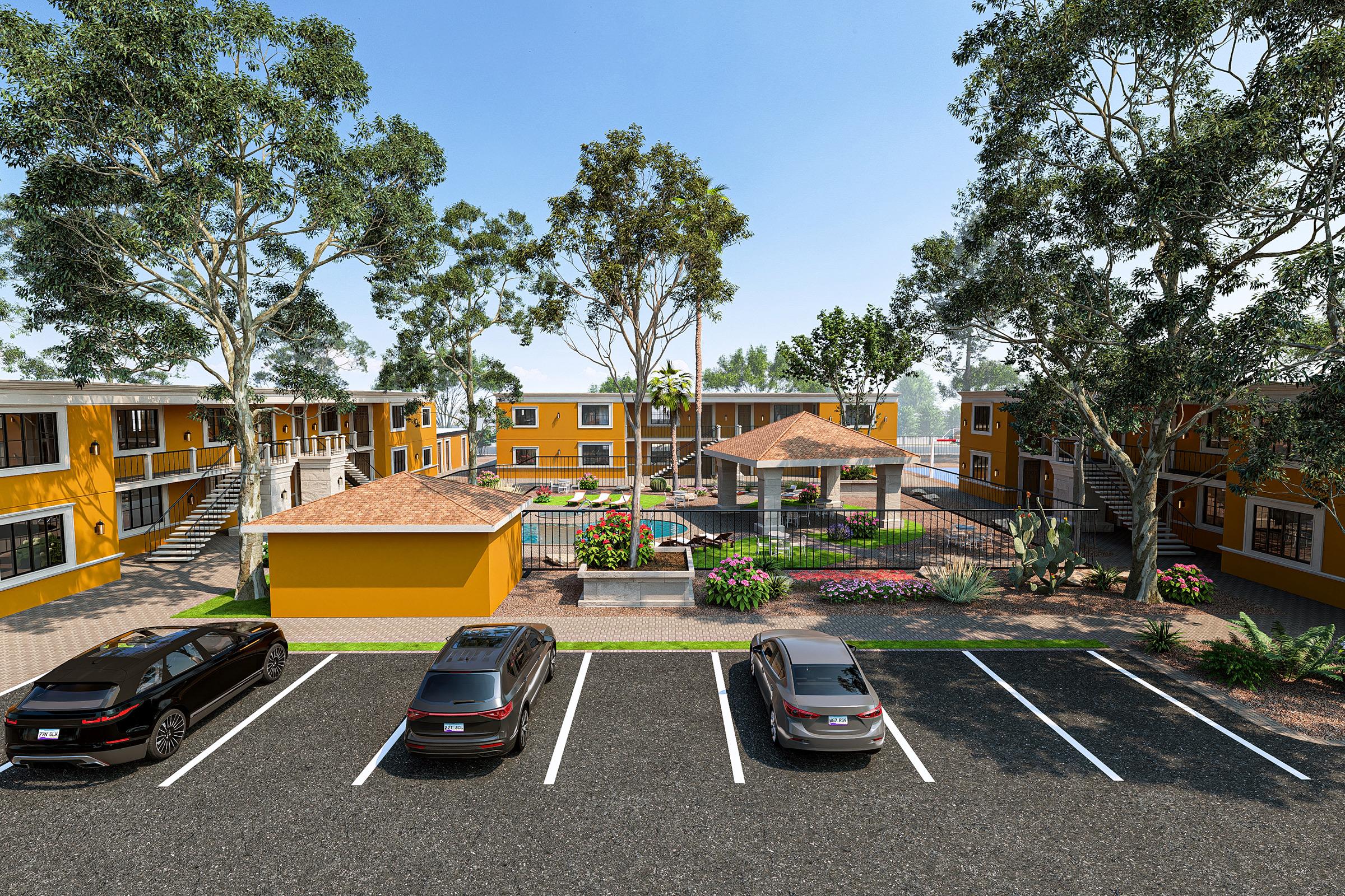 A vibrant residential complex featuring multiple yellow buildings, surrounded by lush greenery and trees. In the center, there is a landscaped area with a gazebo, seating, and a pool. Several parked cars are visible in the foreground, indicating a welcoming community environment.