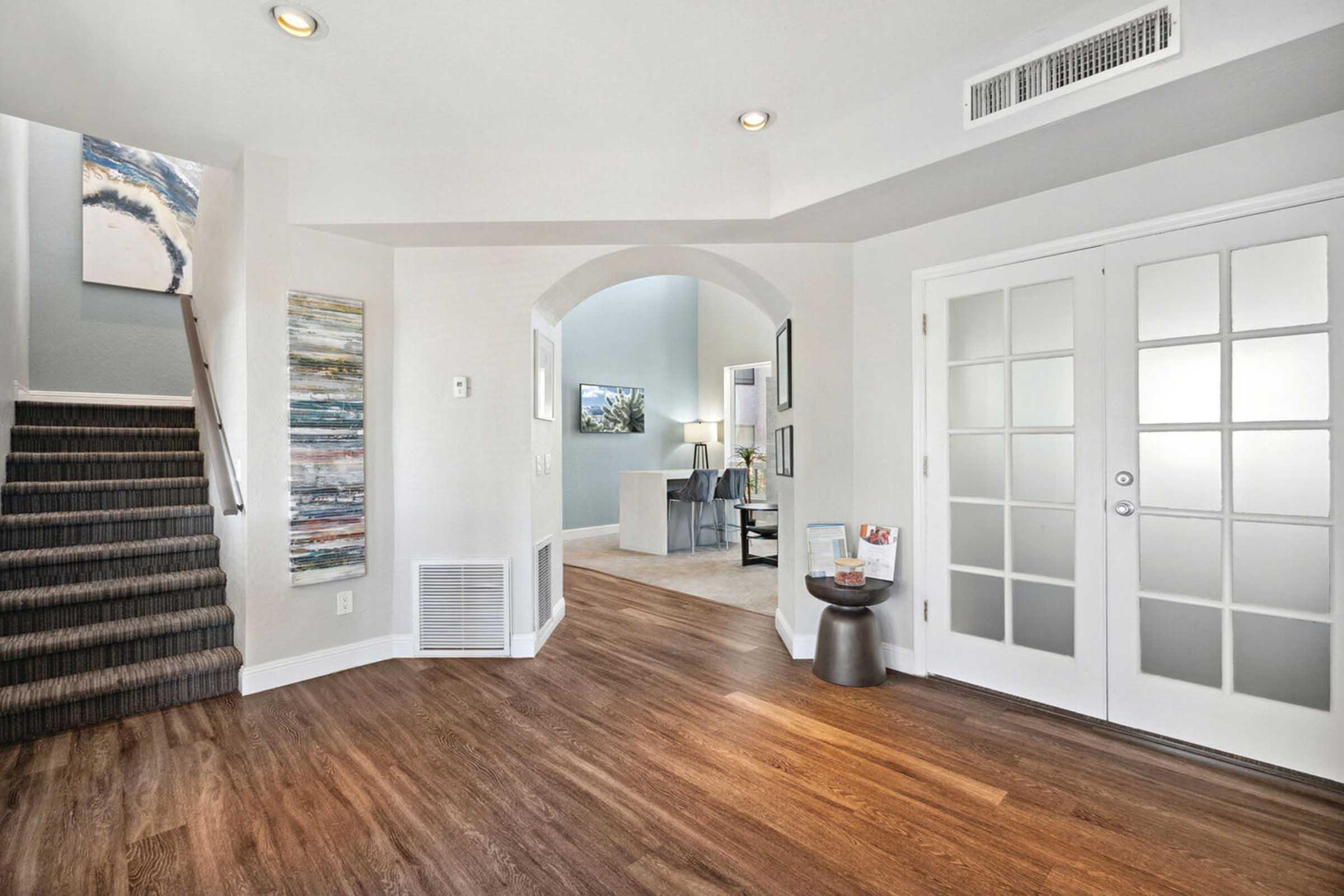 A spacious entryway featuring a staircase to the left, large windows allowing natural light, and stylish decor.
