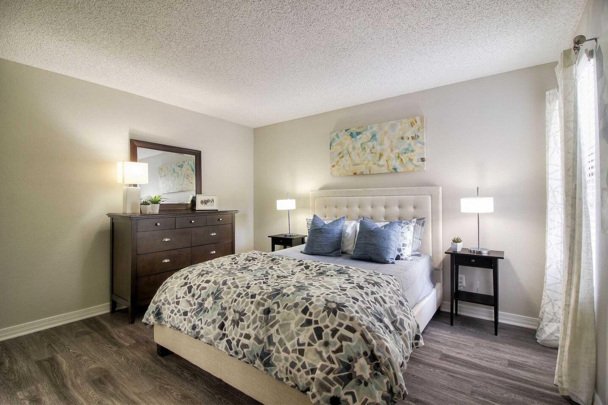 A cozy bedroom featuring a queen-sized bed with a decorative gray and blue patterned comforter.