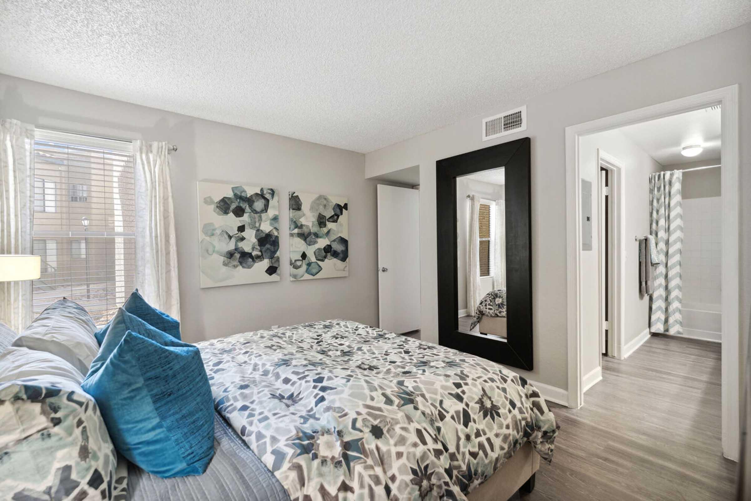 A cozy bedroom featuring a queen-sized bed with a patterned duvet and blue pillows.