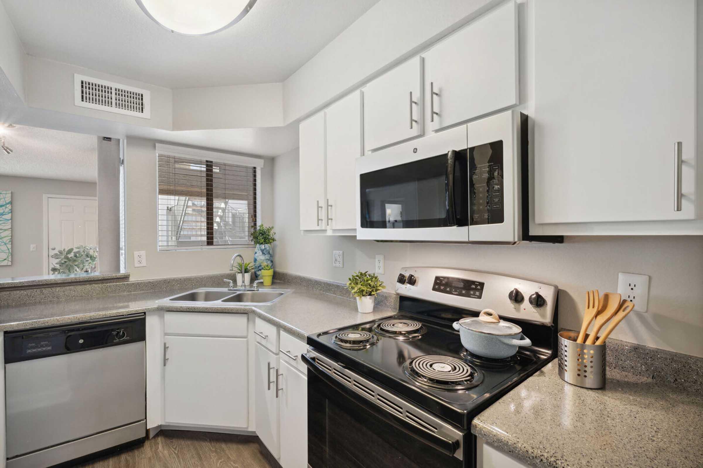 Modern kitchen featuring white cabinets, stainless steel appliances, and a dark countertop.