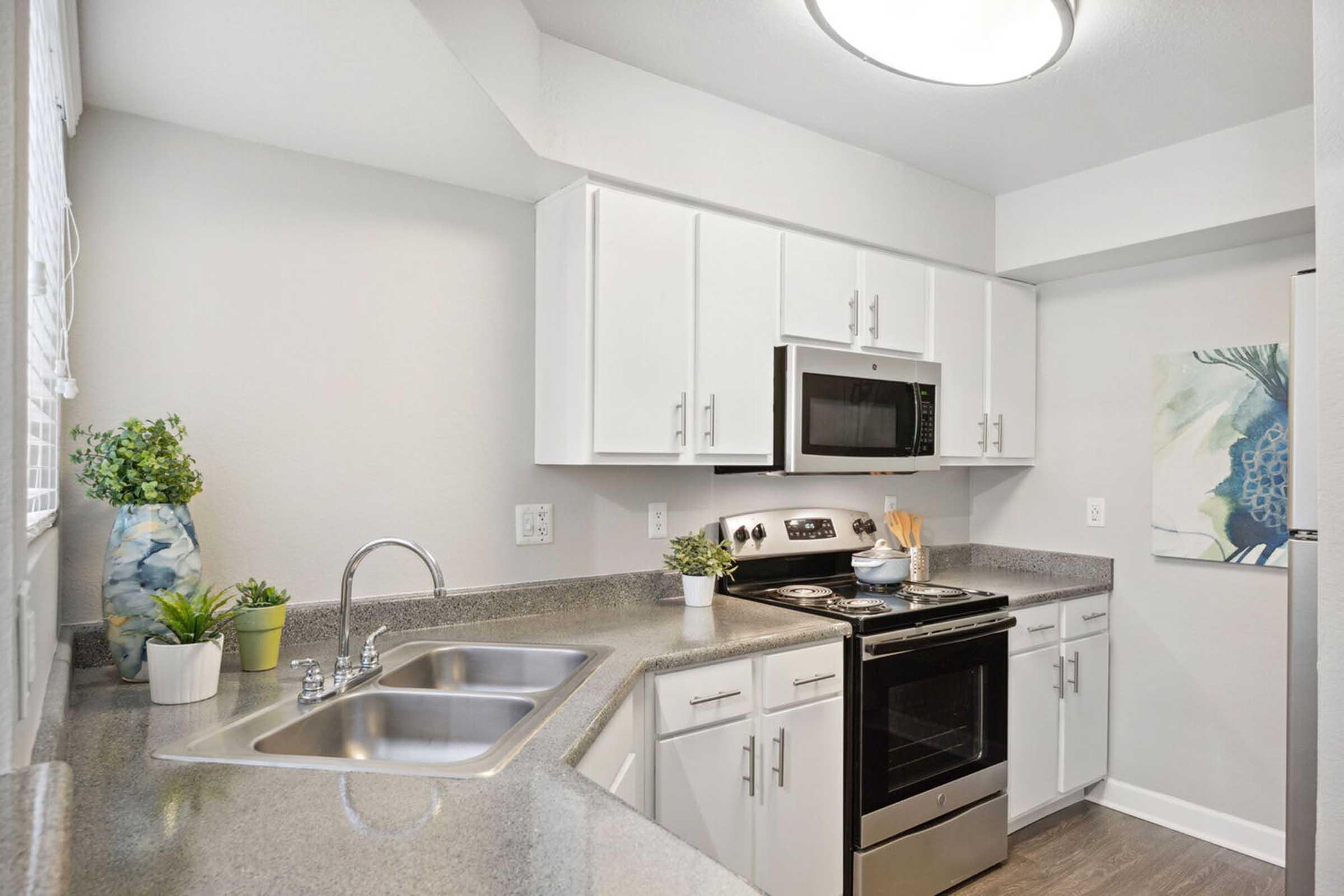 Modern kitchen featuring white cabinets, stainless steel appliances, and a grey countertop.