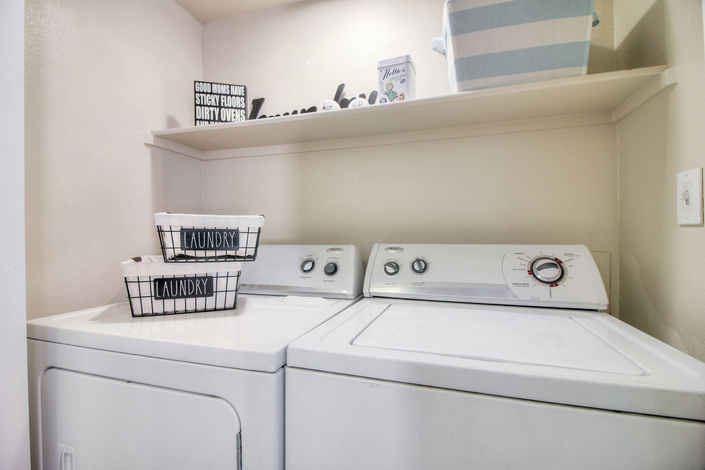 Laundry room featuring a washer and dryer, with a shelf above displaying decorative items.