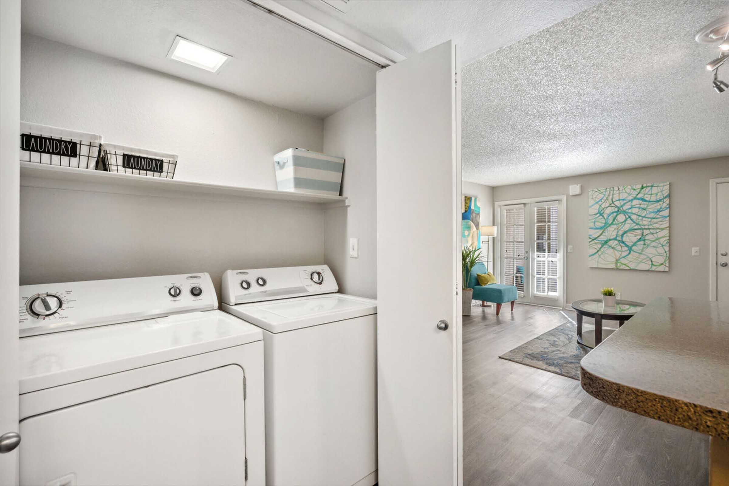 A laundry area featuring a washer and dryer, with a shelf above holding baskets labeled "LAUNDRY."