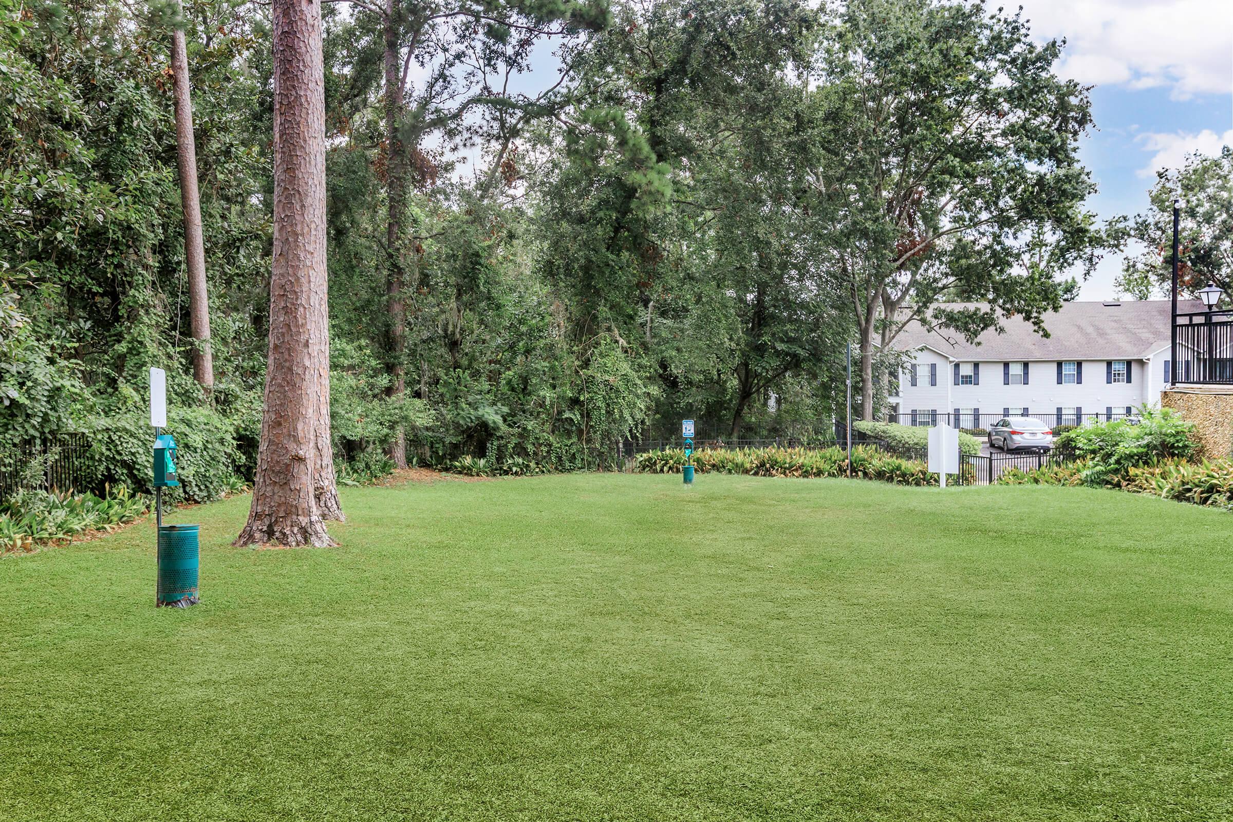 a large green field with trees in the background