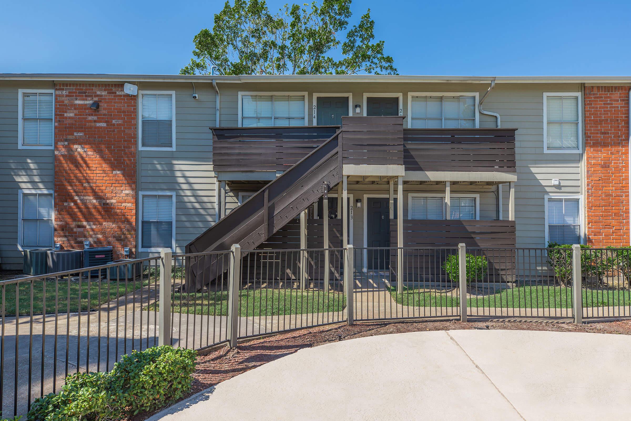 a house with a fence in front of a brick building