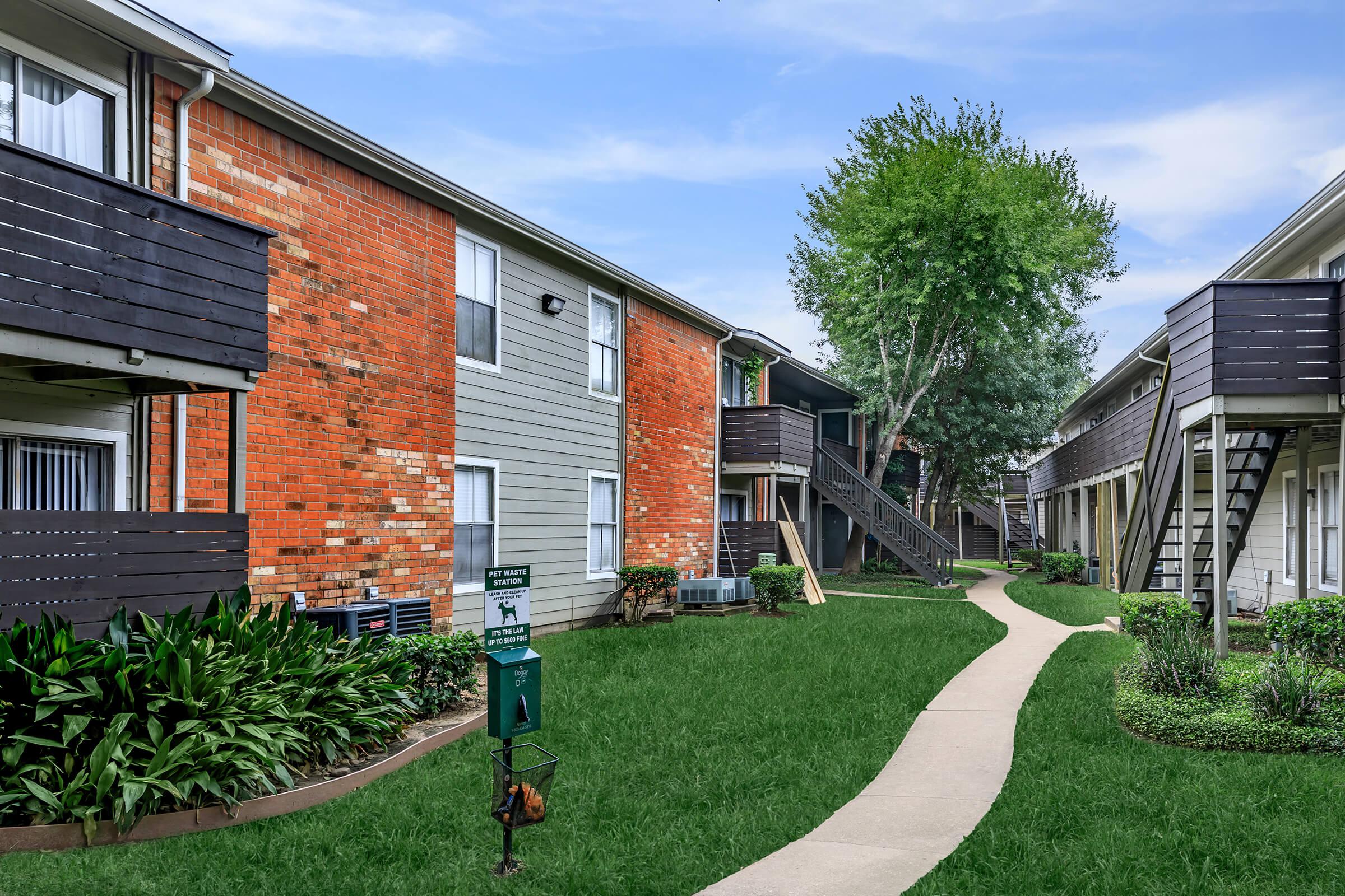 a house with a lawn in front of a brick building