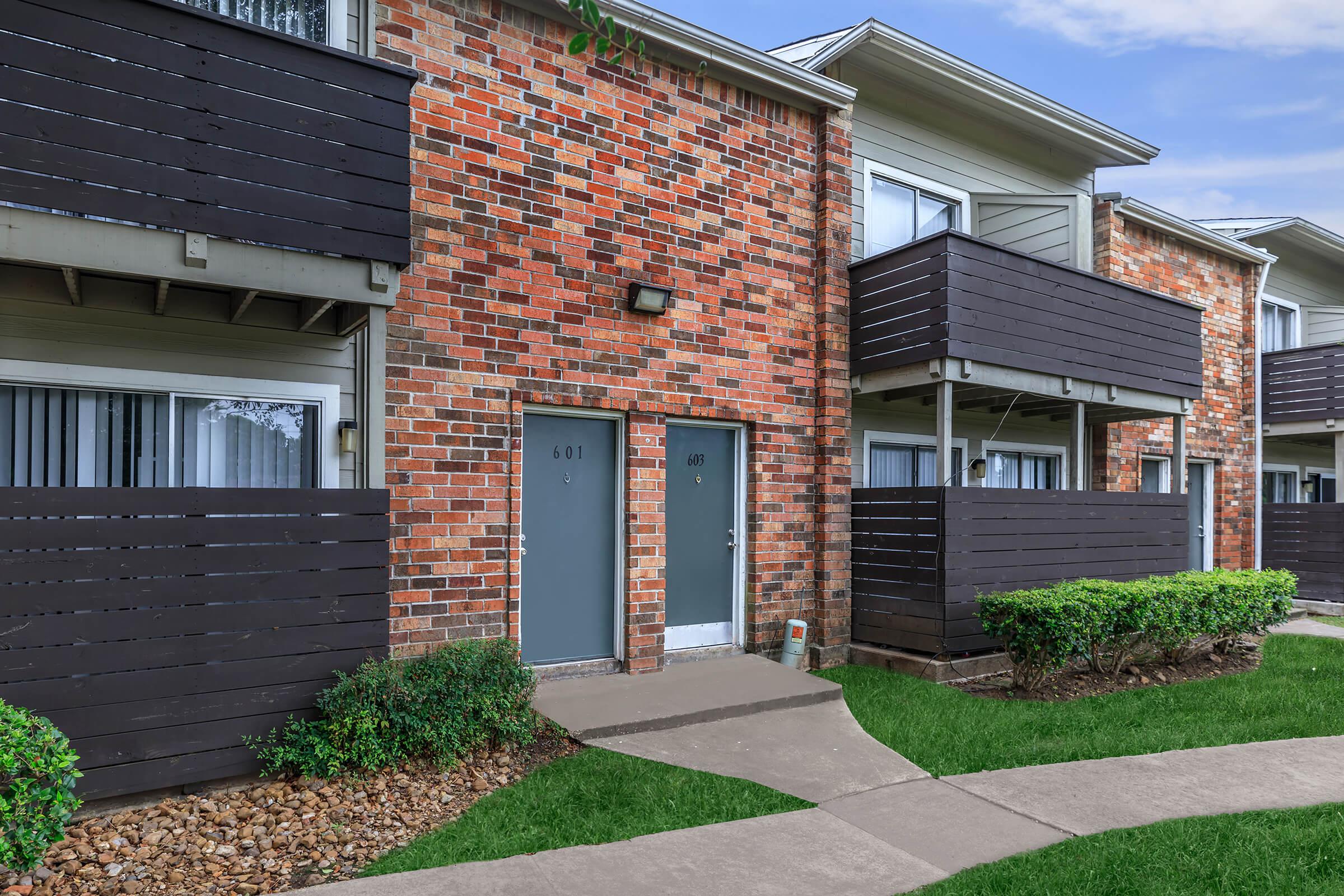 a house with a lawn in front of a brick building