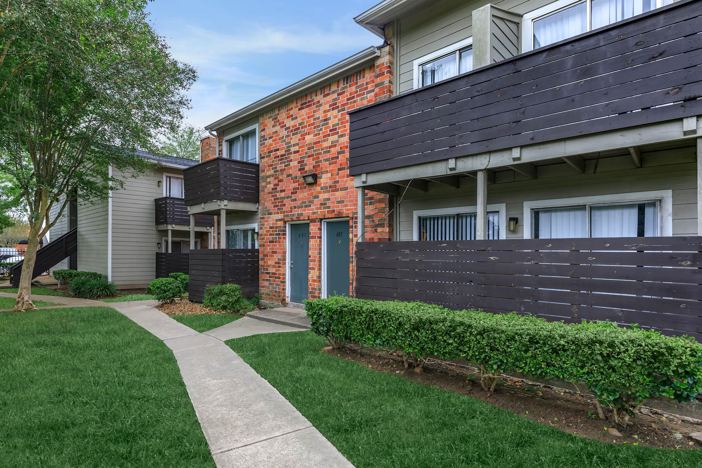 a house with a lawn in front of a brick building