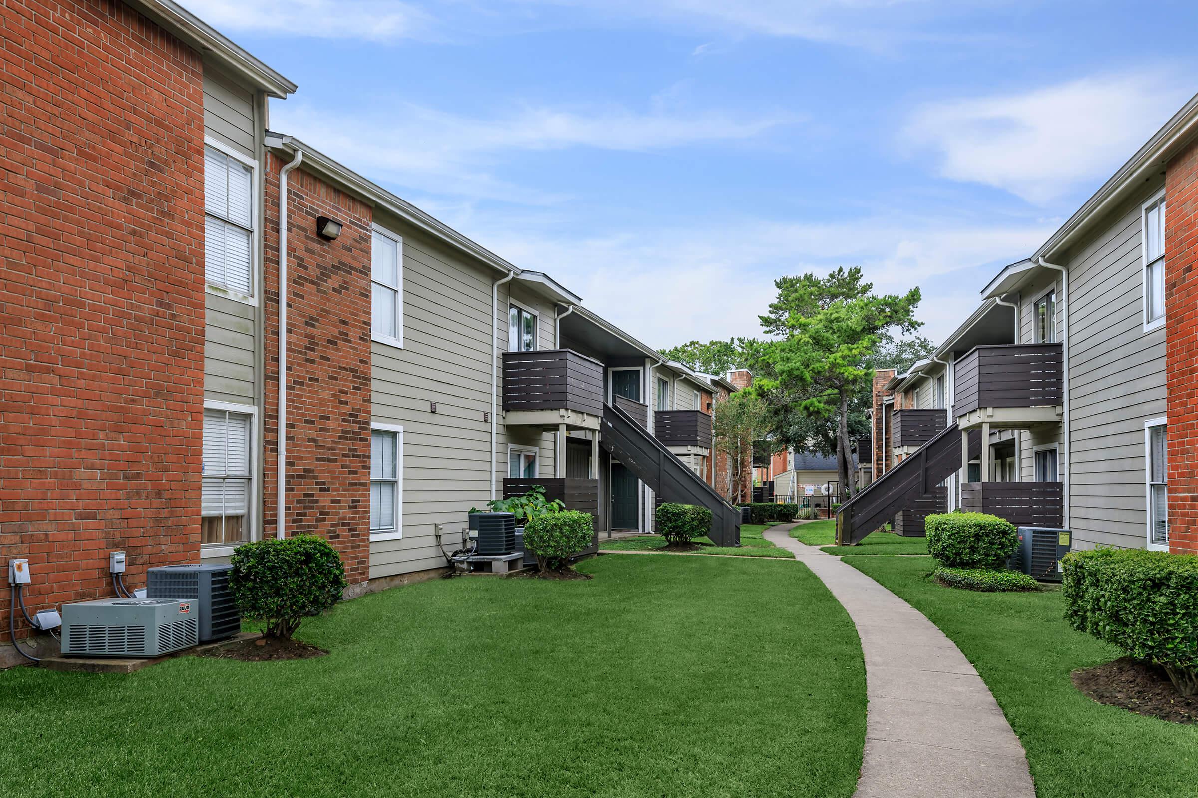 a house with a lawn in front of a brick building