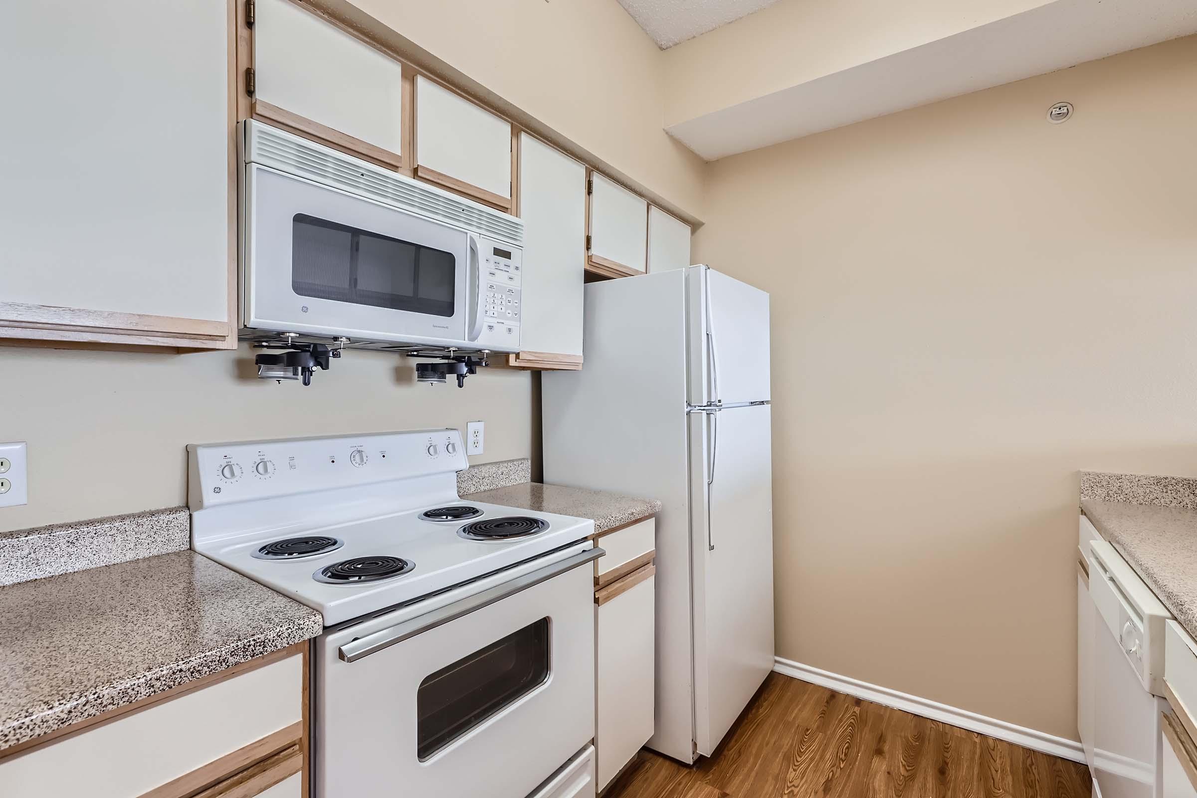 A kitchen with white cabinets and white appliances at Rise Skyline. 