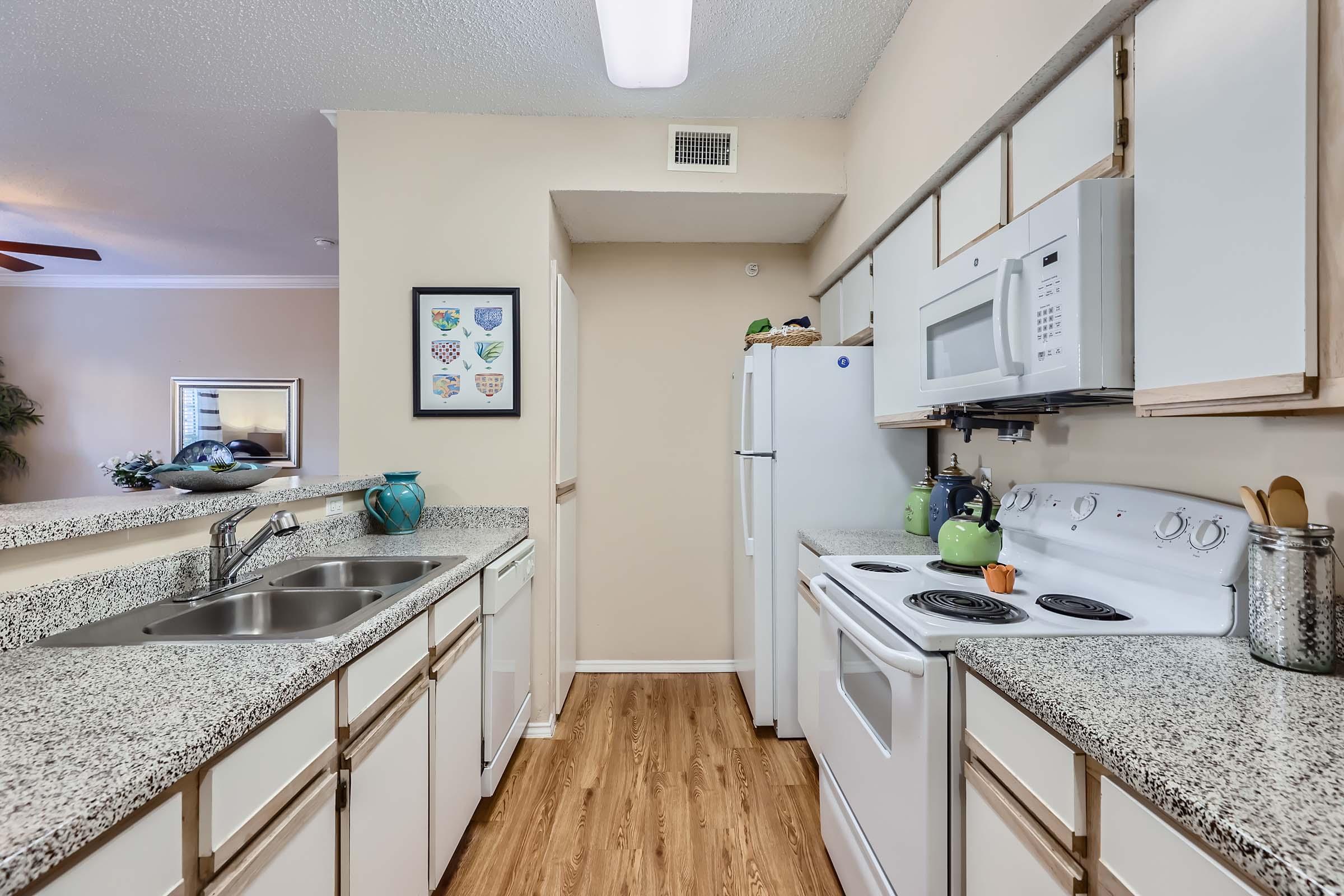 Rise Skyline apartment kitchen with white cabinets and white appliances. 