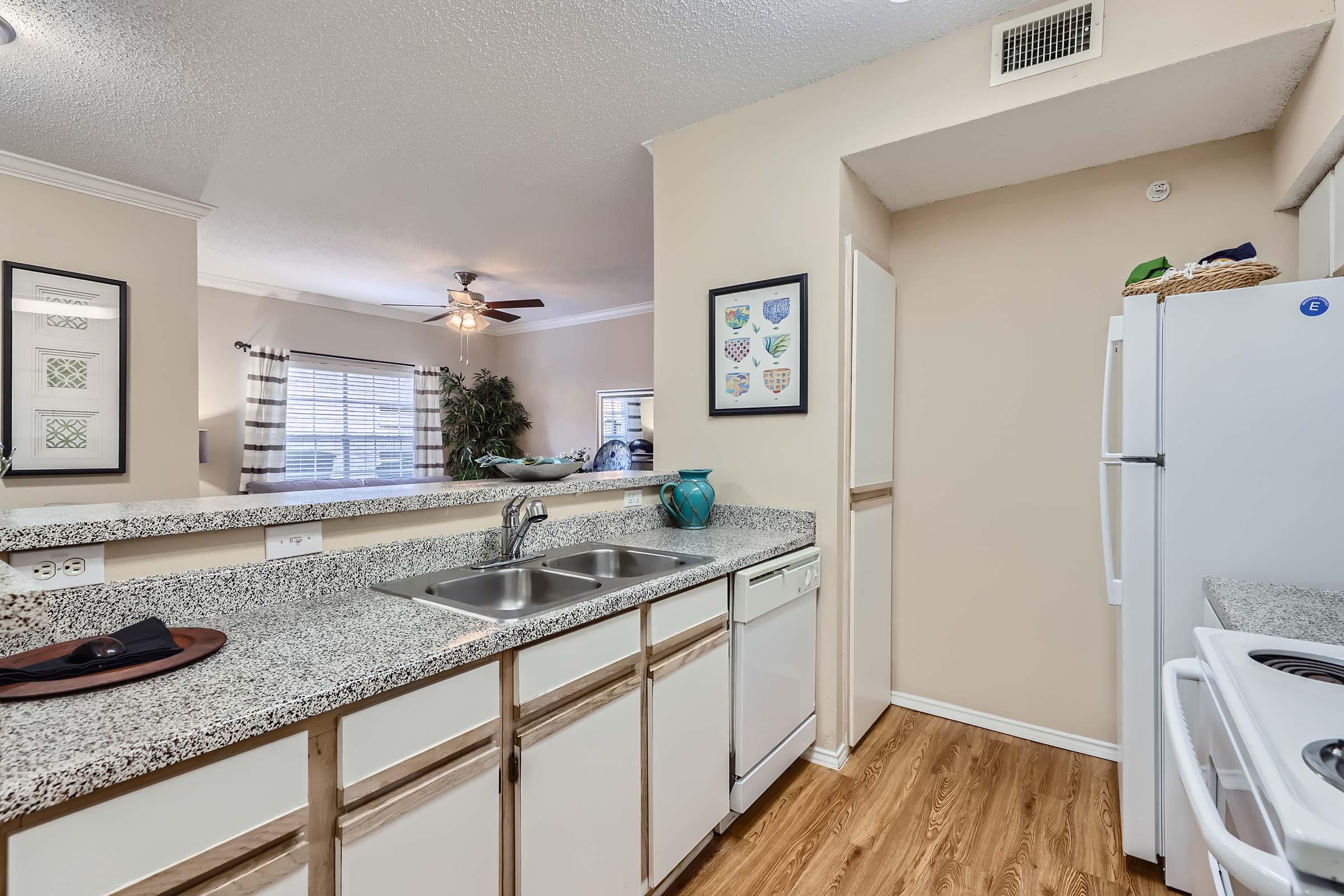 The kitchen with white cabinets near the living area with a big window at Rise Skyline.