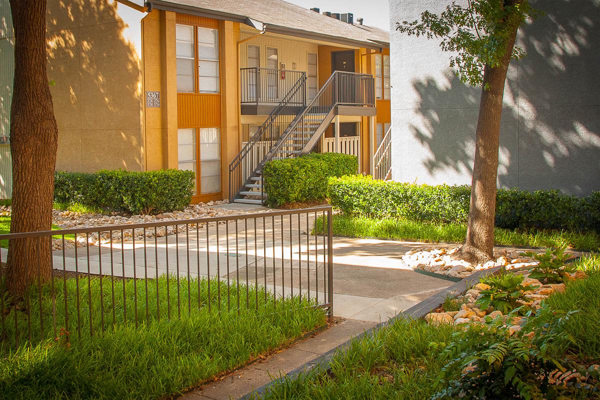 The Way Apartments community building with green shrubs