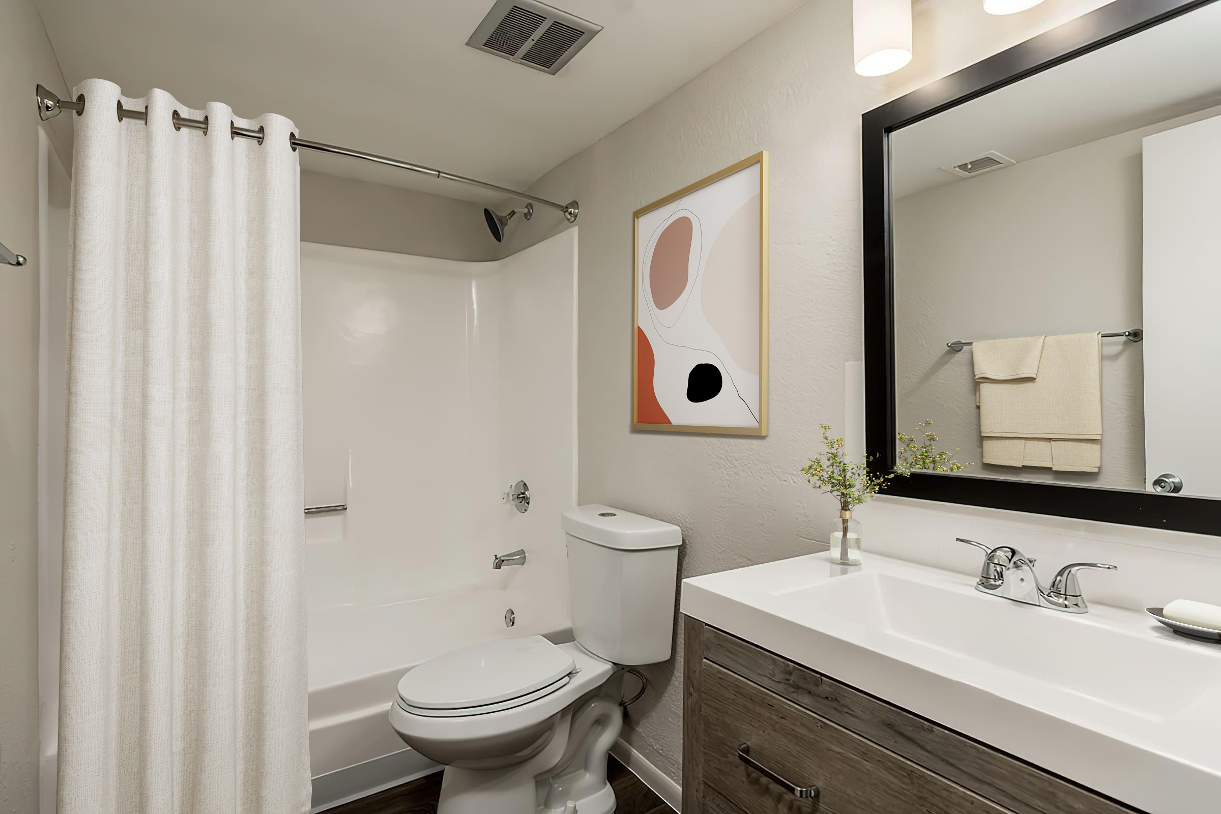 A modern bathroom featuring a white bathtub with a shower curtain, a white toilet, and a sleek vanity with a sink. The vanity has a mirror above it and a small plant decoration. A piece of abstract art hangs on the wall, adding a touch of color to the neutral-toned space.