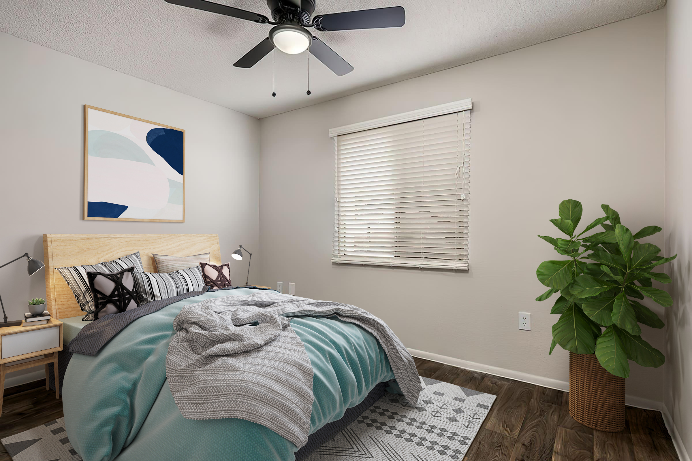 A cozy bedroom featuring a bed with blue and gray bedding, decorative pillows, a wooden headboard, and a light-colored wall. There's a ceiling fan, a window with blinds, and a potted plant in the corner. A piece of abstract wall art hangs above the bed, and a light rug lies on the floor.