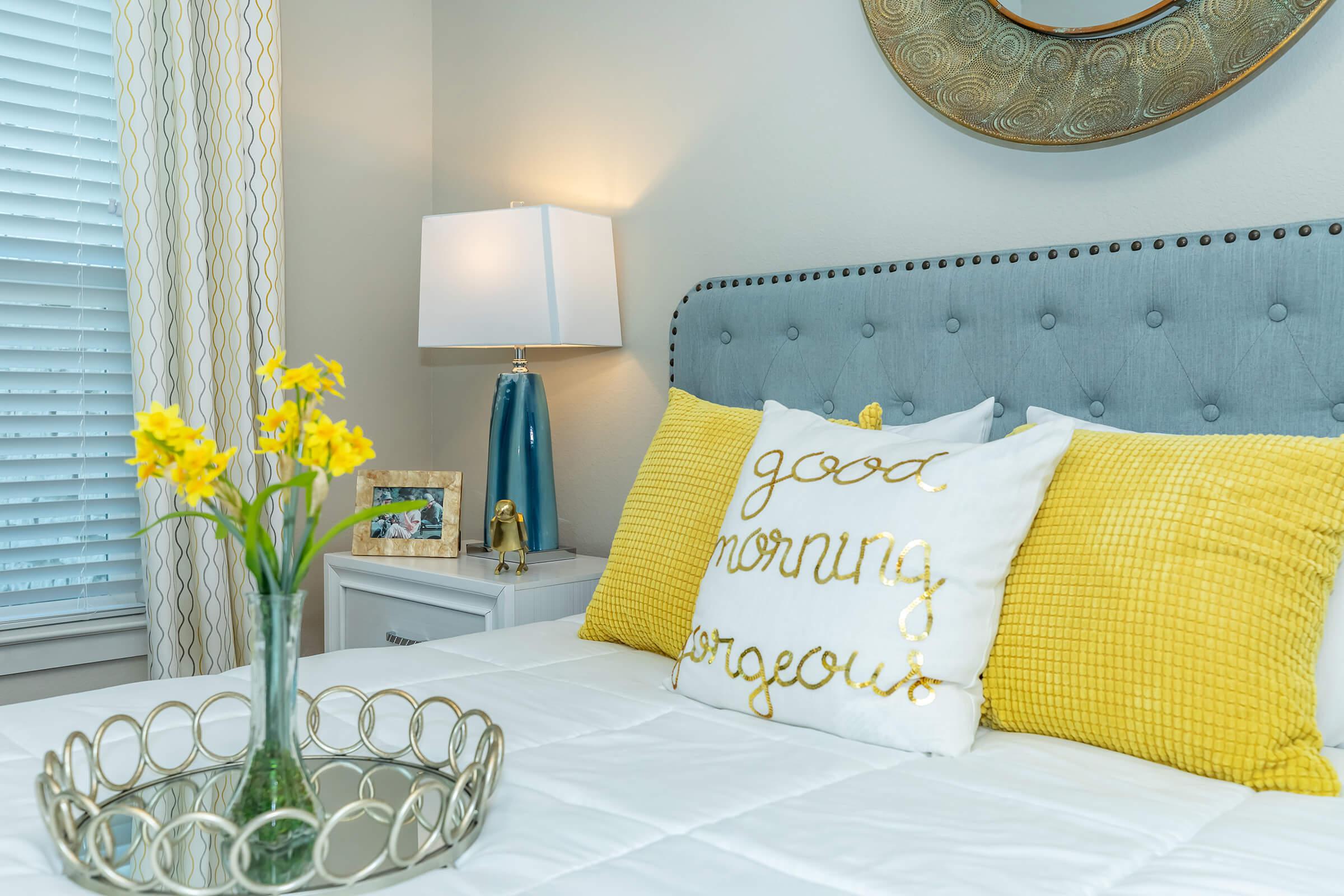 a bedroom with a bed and a vase of flowers on a table