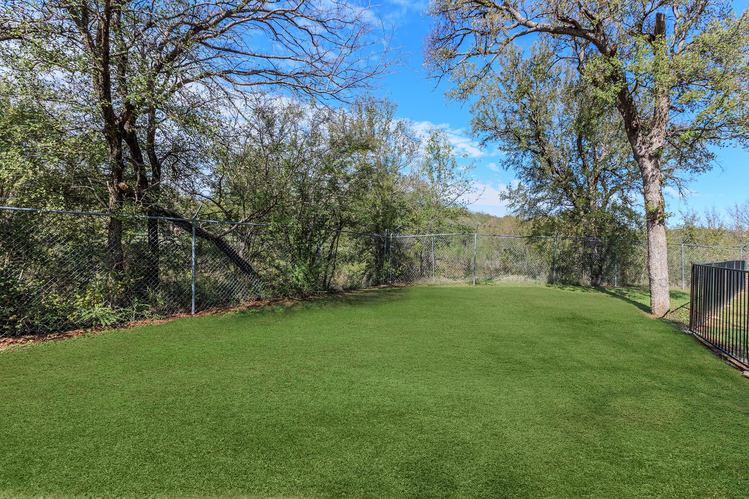 a large green field with trees in the background