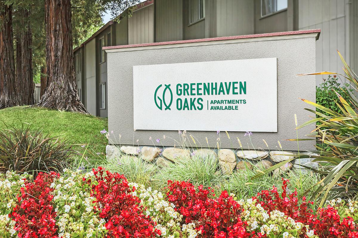 a sign above a flower garden