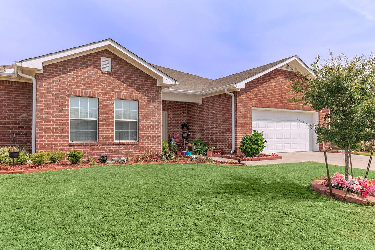 a large brick building with grass in front of a house
