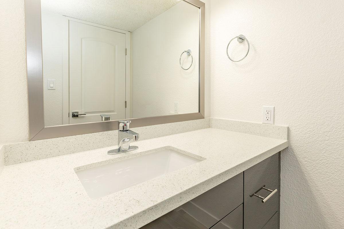 a white sink sitting under a mirror