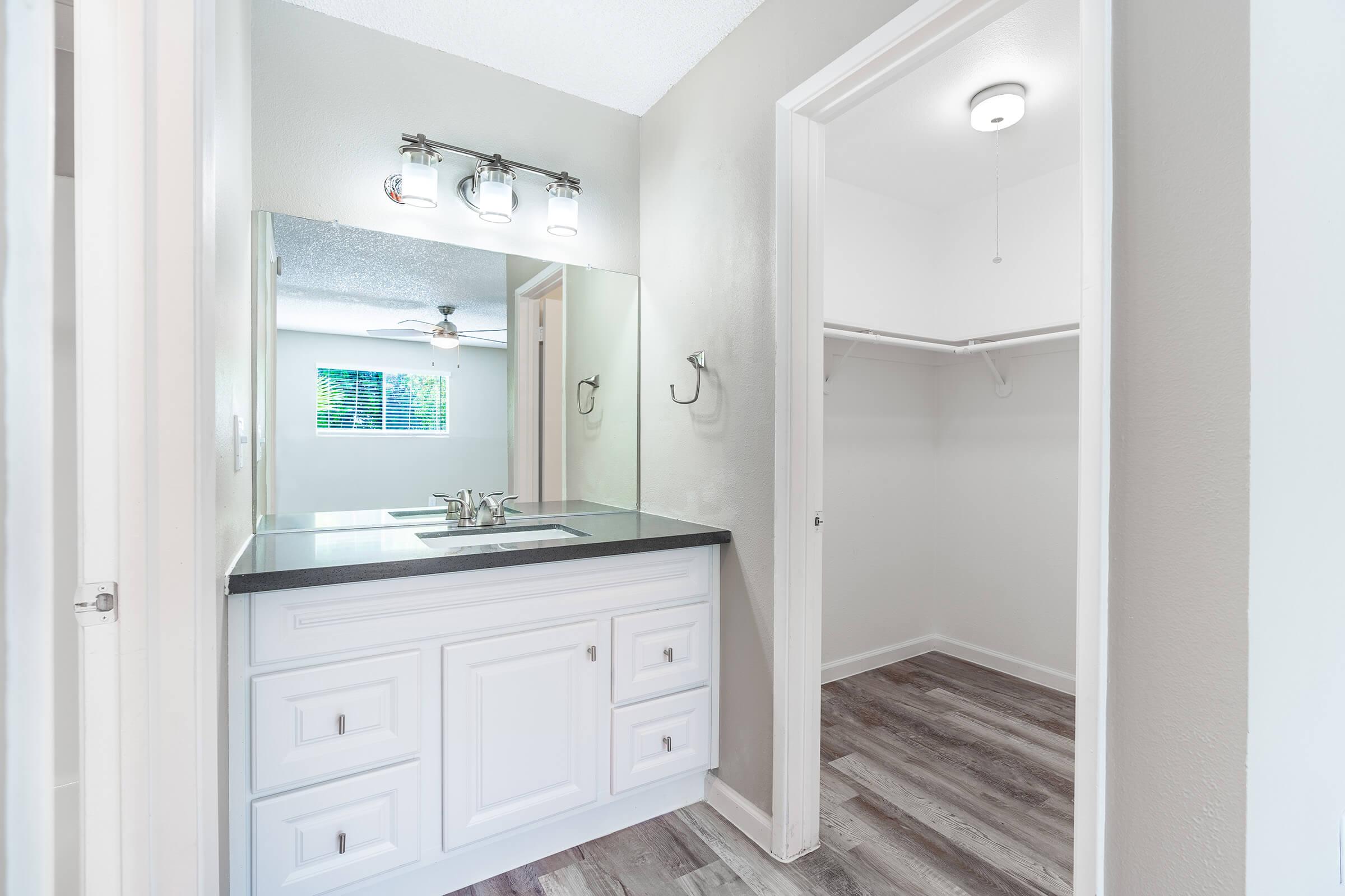 Bright Mesa apartment bathroom with white cabinets and attached walk-in closet