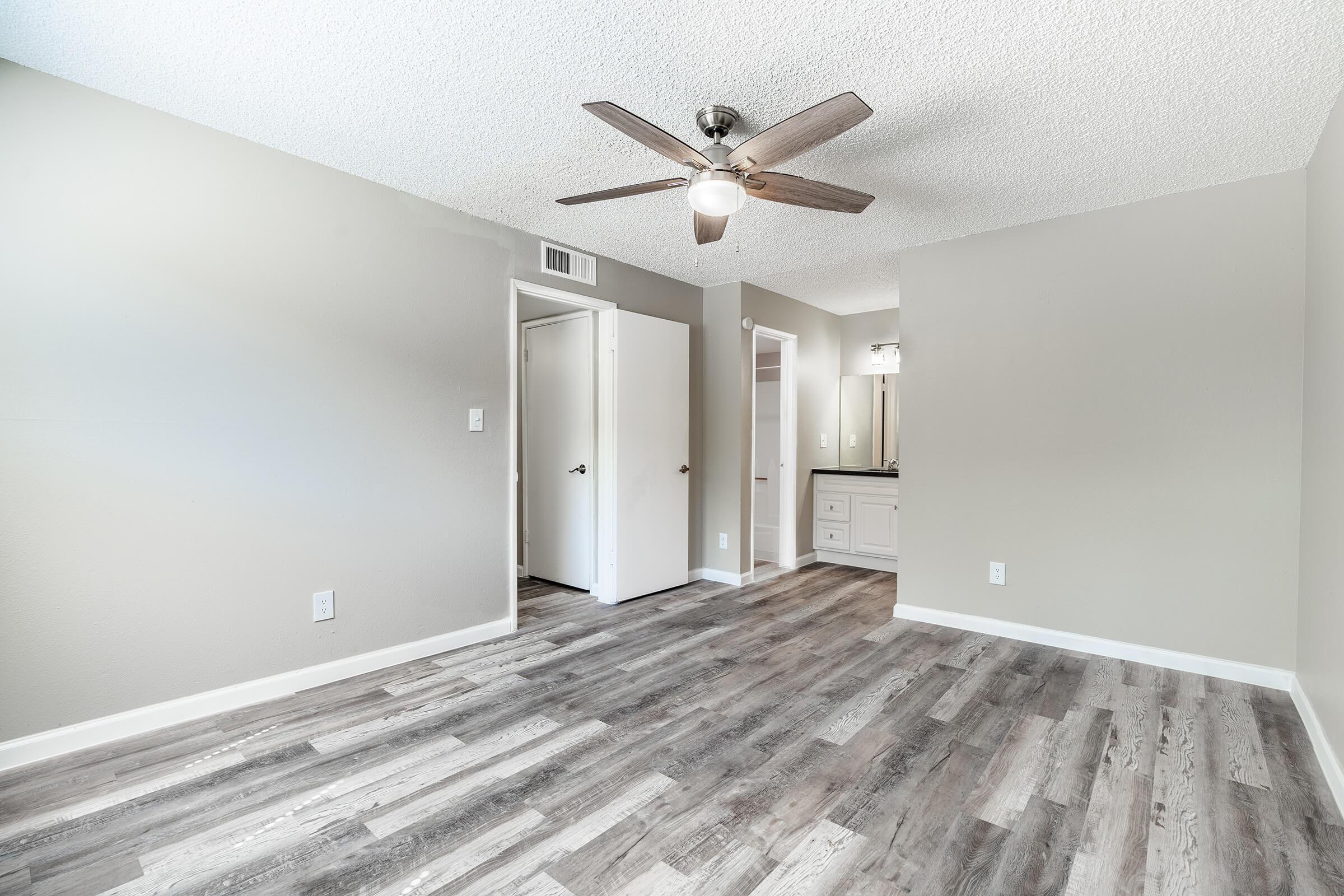 Spacious modern open Mesa, AZ apartment bedroom with ceiling fan and grey wood floors
