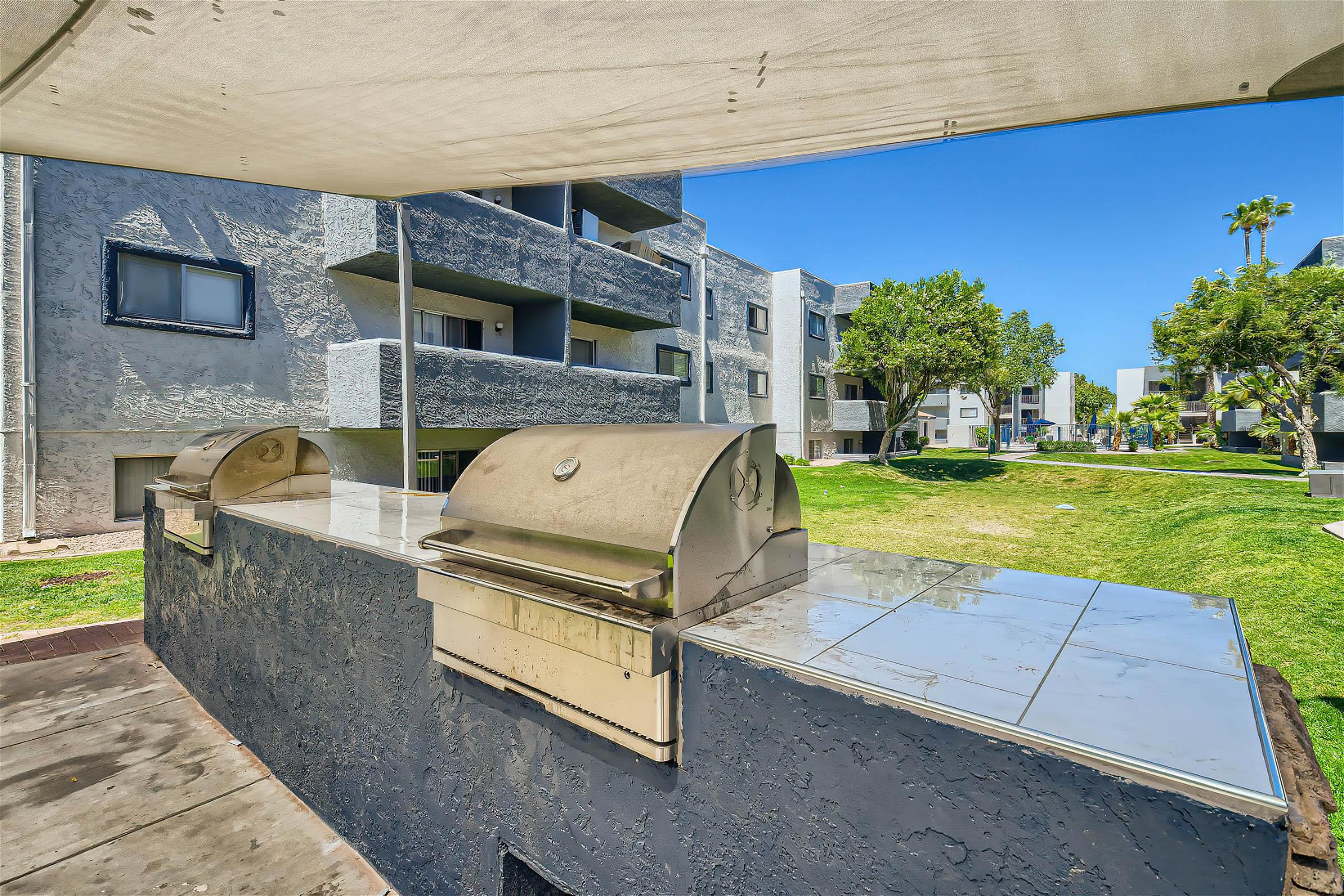 Closeup view of the Rise at Dobson Ranch outdoor grilling area with two gas grills under a canopy