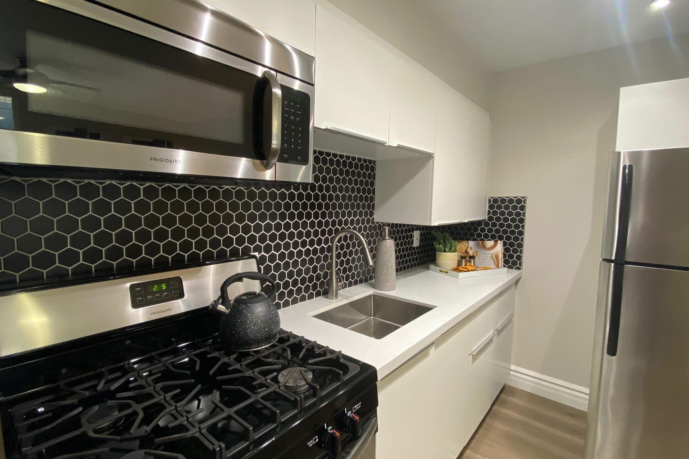 a stove top oven sitting inside of a kitchen with stainless steel appliances