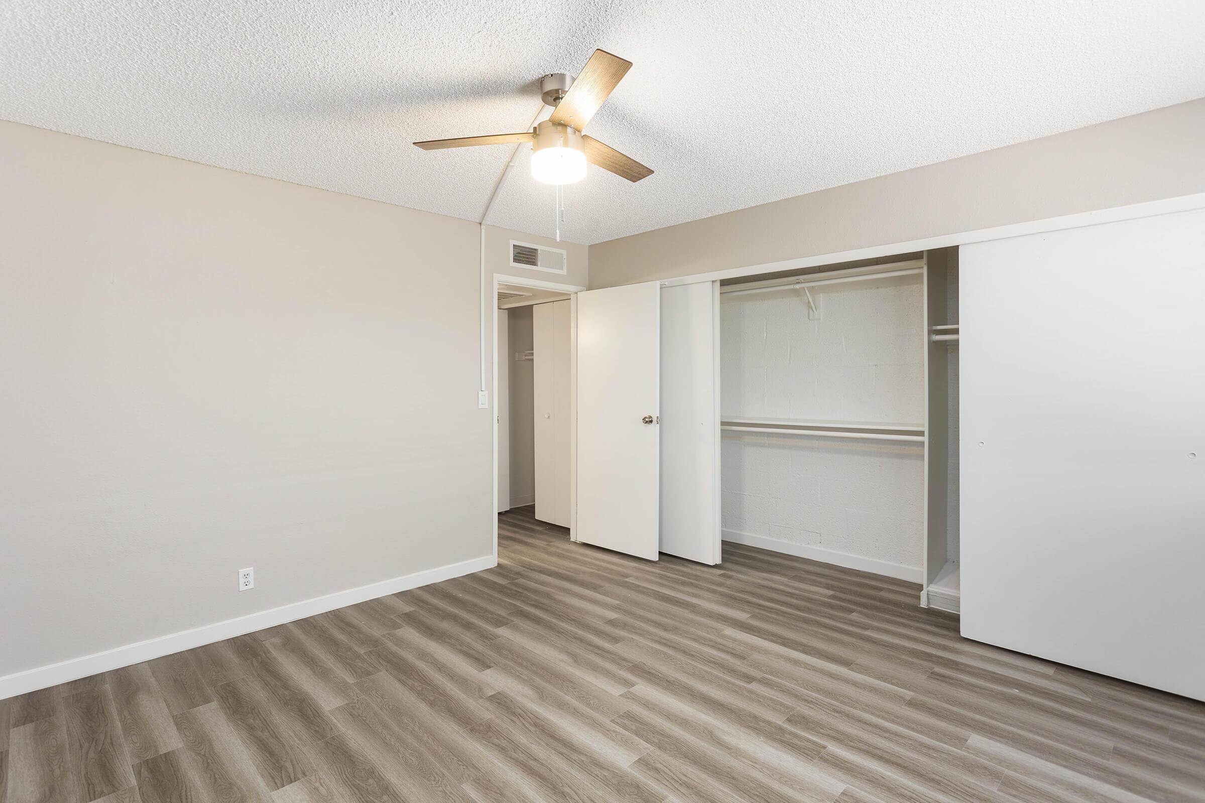 Open bright large main bedroom with ceiling fan and large sliding door closet