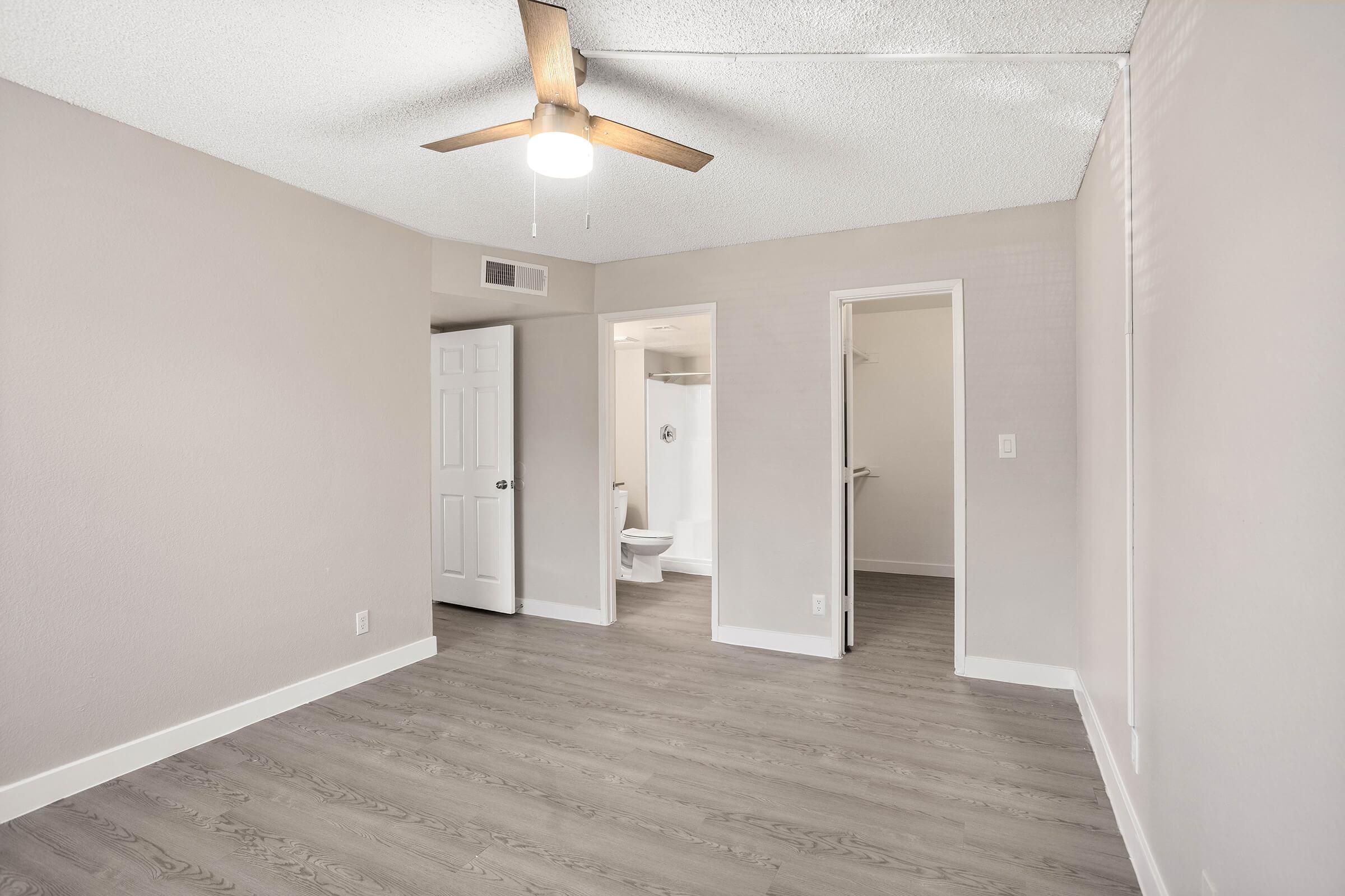 Open bright bedroom with ceiling fan, walk in closet, and attached bathroom