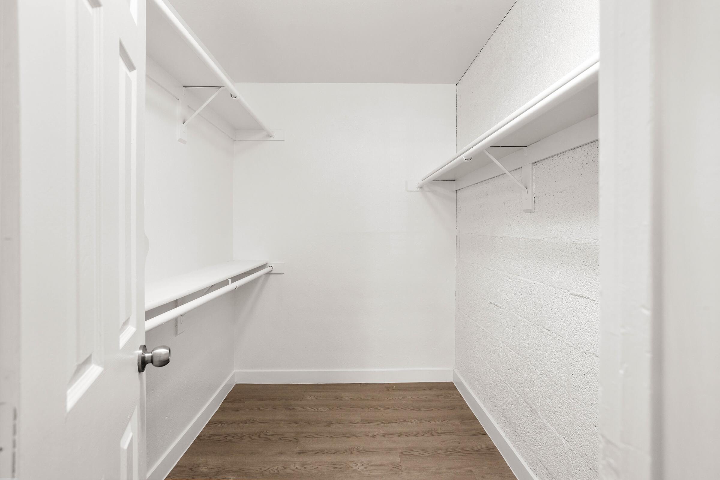 White walk in closet with wood flooring and large white shelves