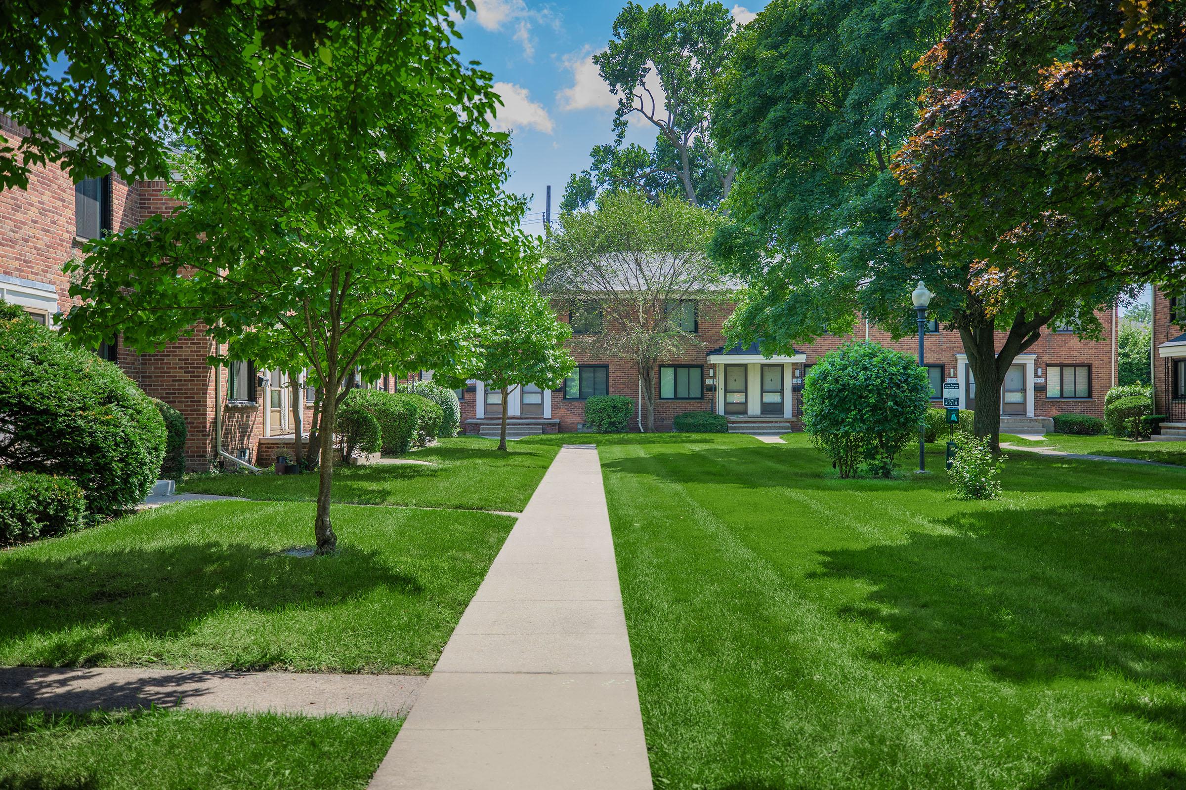 a path with grass in front of a brick building