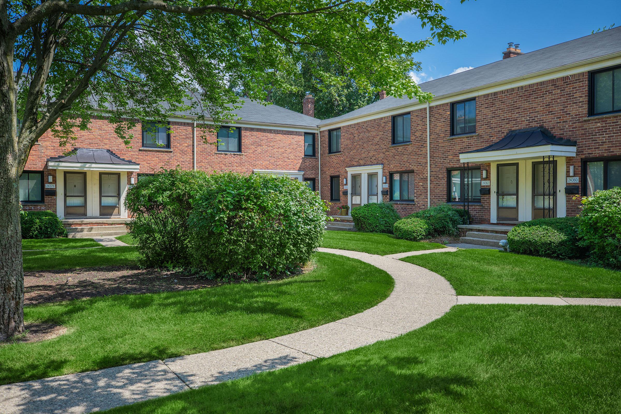 a large brick building with grass in front of a house