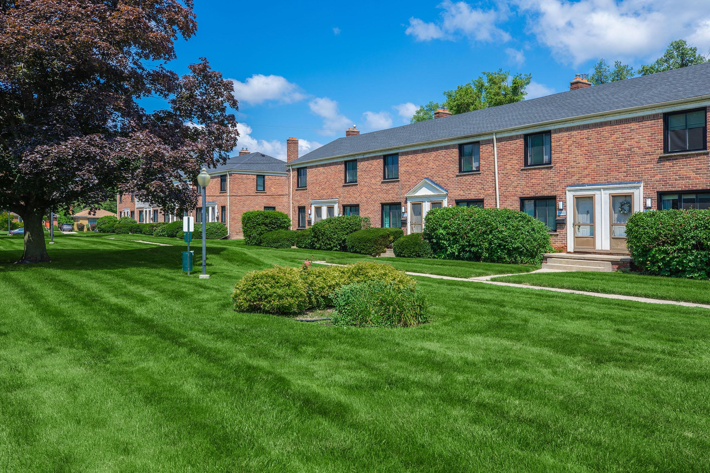 a large brick building with green grass in front of a house