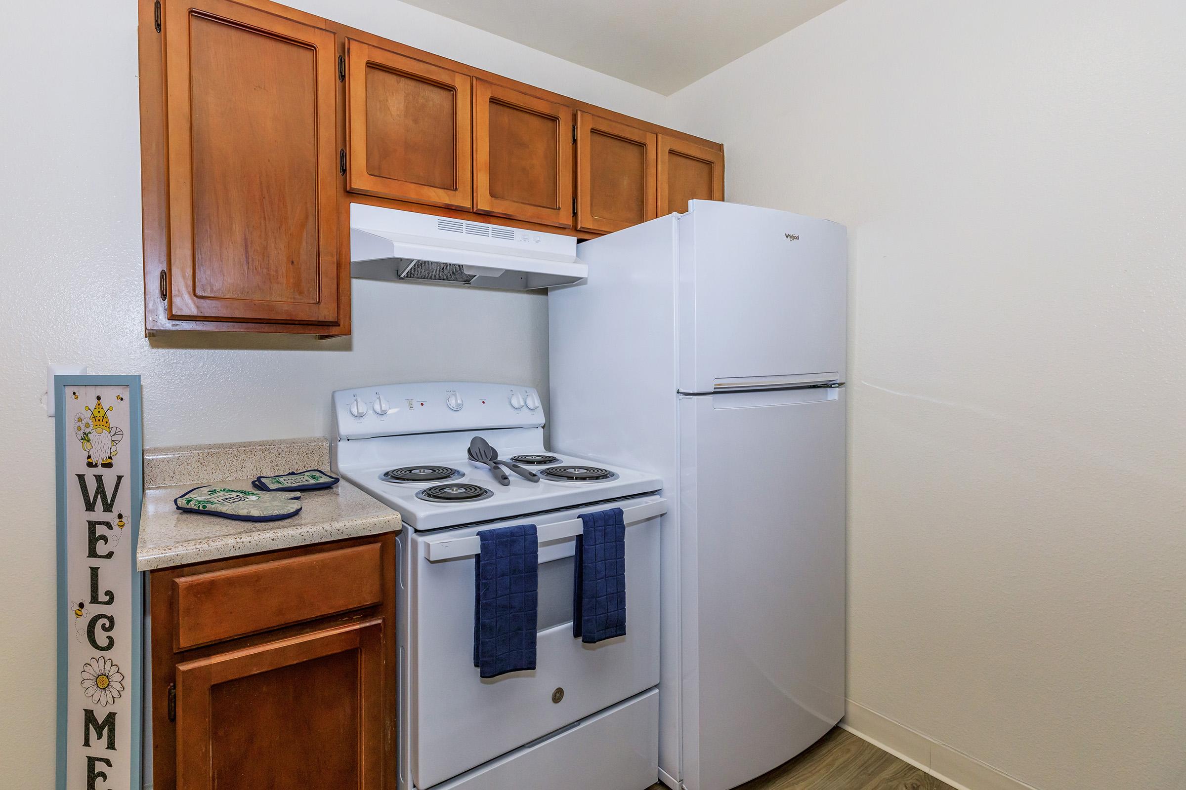 Kitchen with white appliances, wood cabinets and a refrigerator.