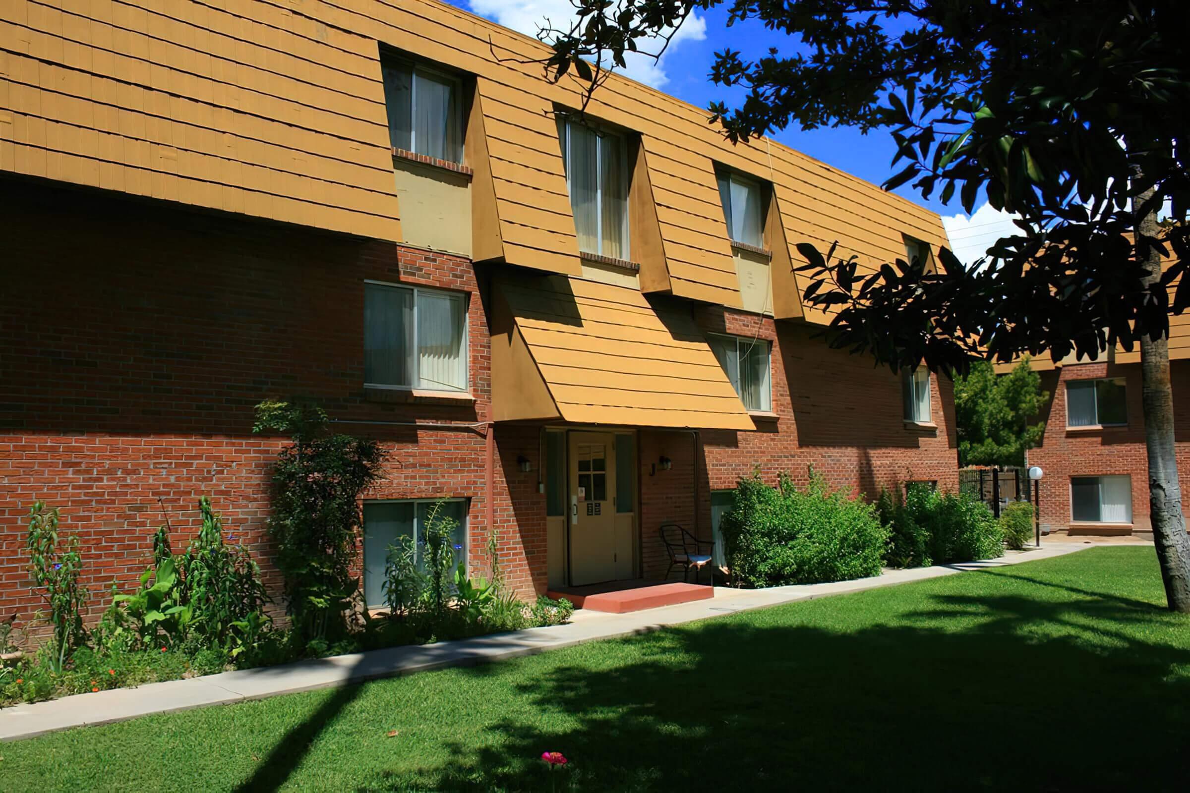 a house with bushes in front of a brick building
